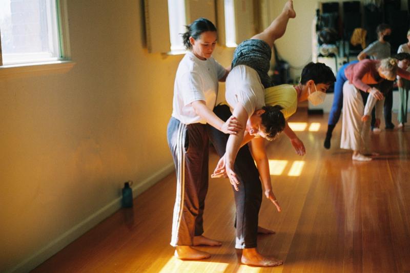 women practising a contact improvisation balance in a sunny dance studio