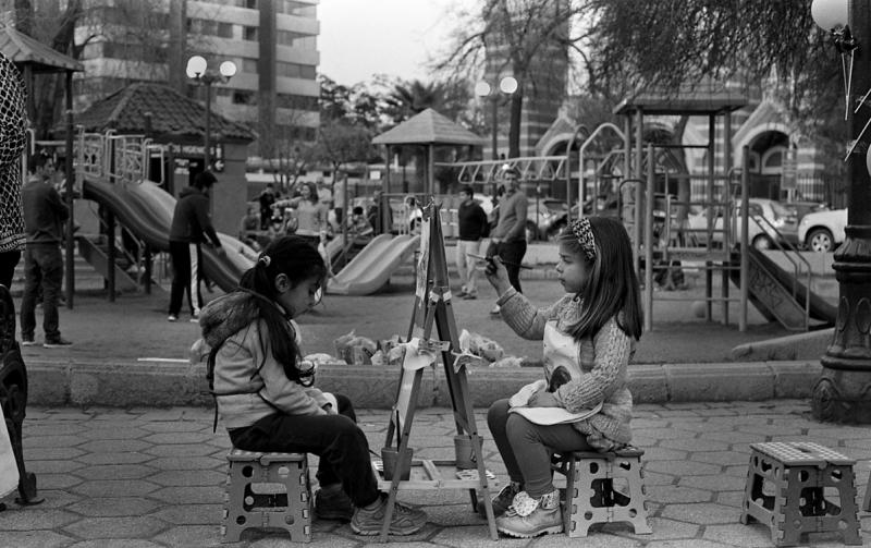 a black and white photo of two young children painting at a playground