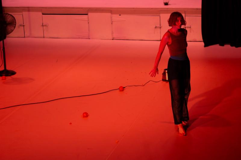 a dancer stands on the right of a white stage with red lighting
