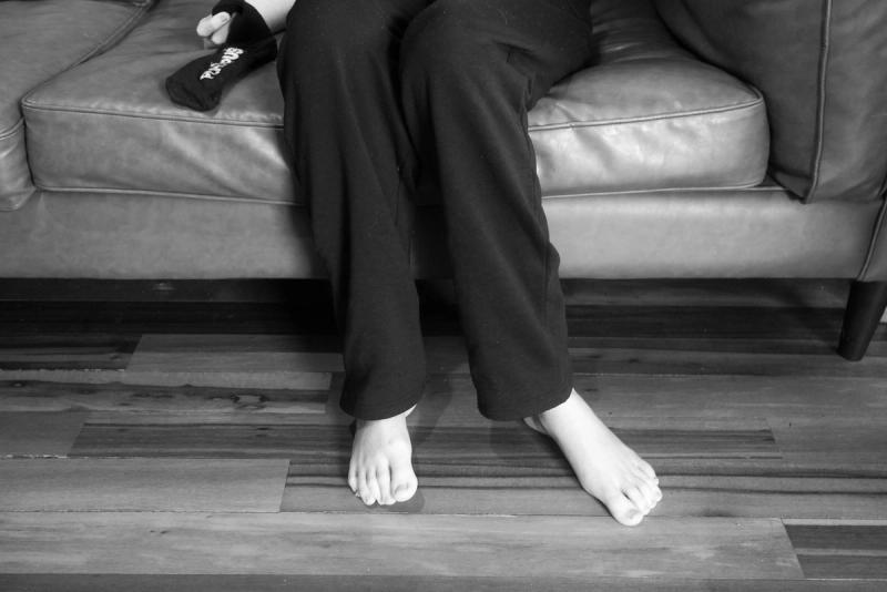 black and white photo of a boys legs sitting on a couch