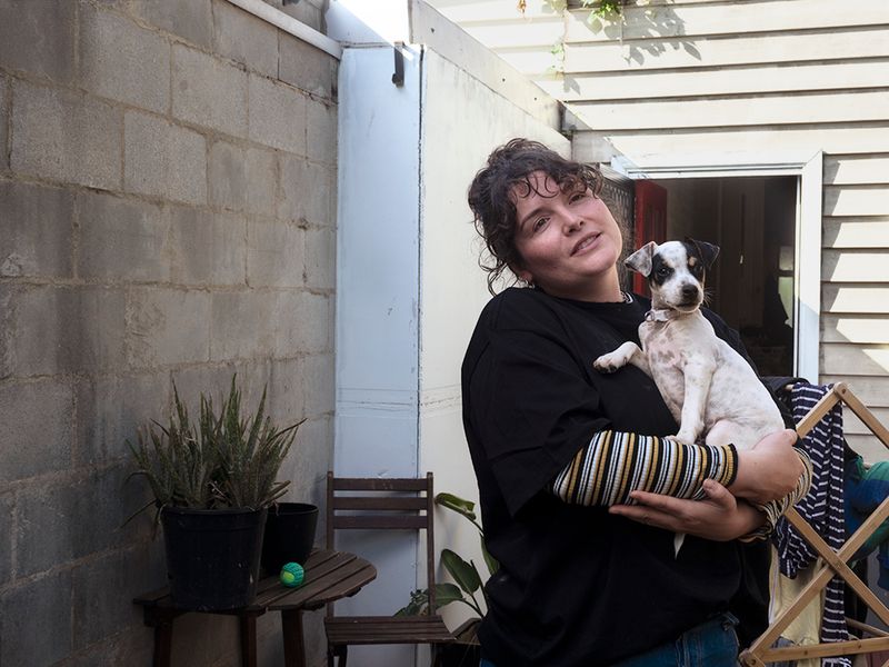 a woman in a backyard holding a puppy and looking in the distance