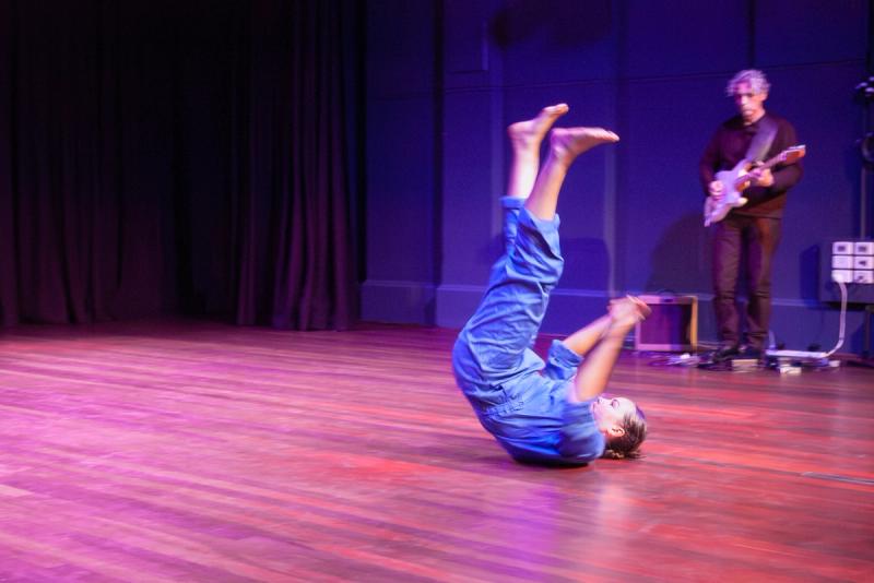 a dancer in a blue outfit has their feet in the air