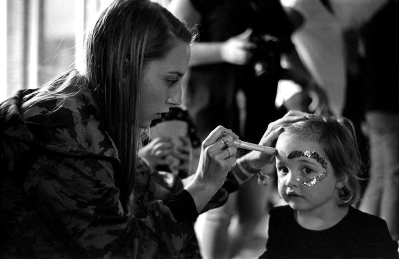 a black and white photo of someone painting a child's face