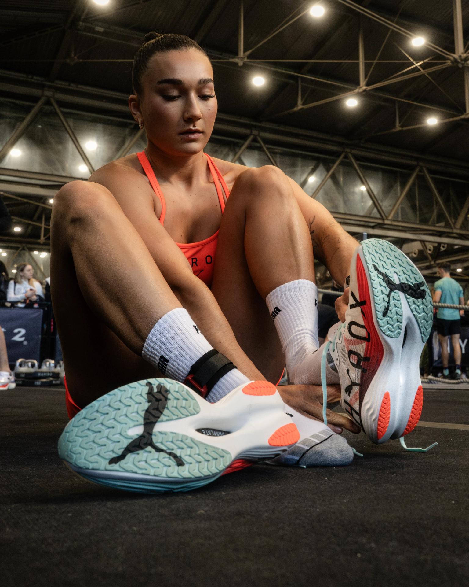 a woman sits on the floor tying her puma shoes