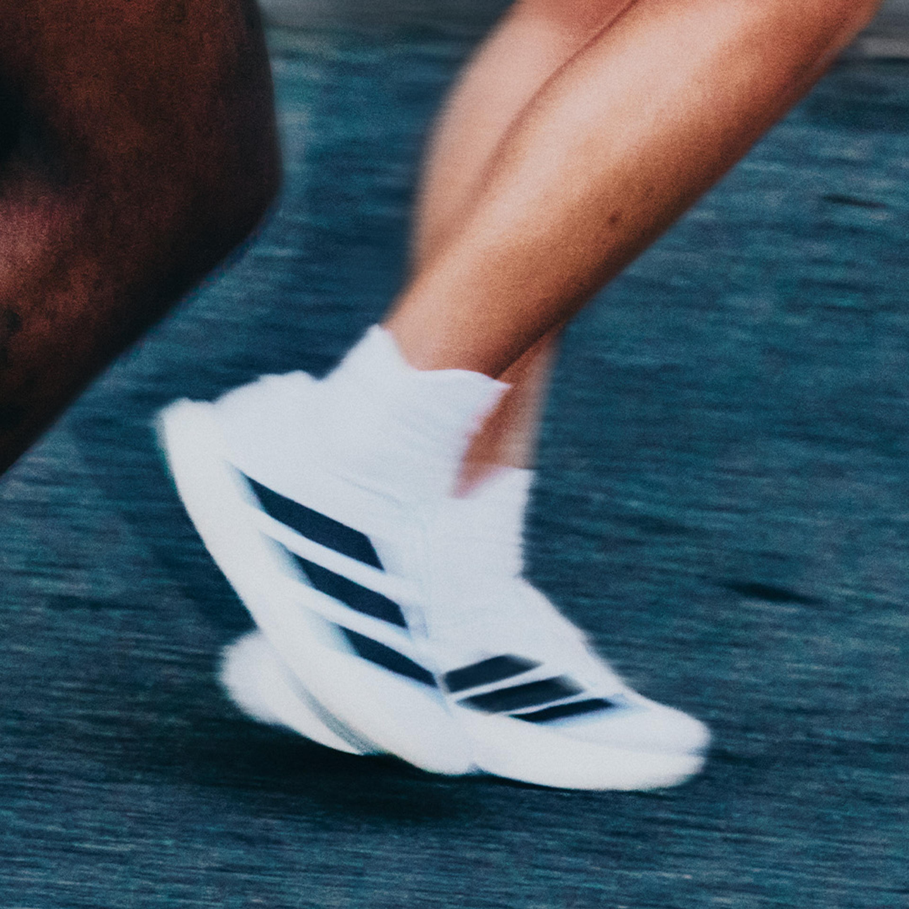 Two runners in motion blur, one with a "5 ICON" tattoo, the other wearing white Adidas sneakers.
