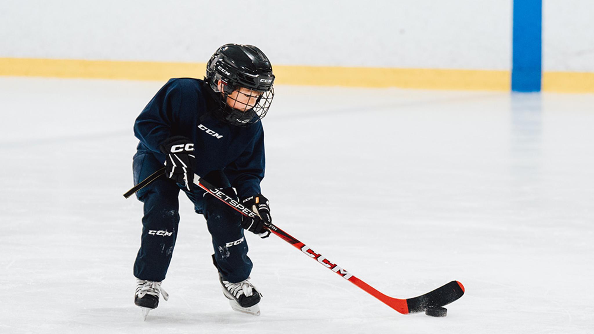 a young boy is playing ice hockey on a rink .