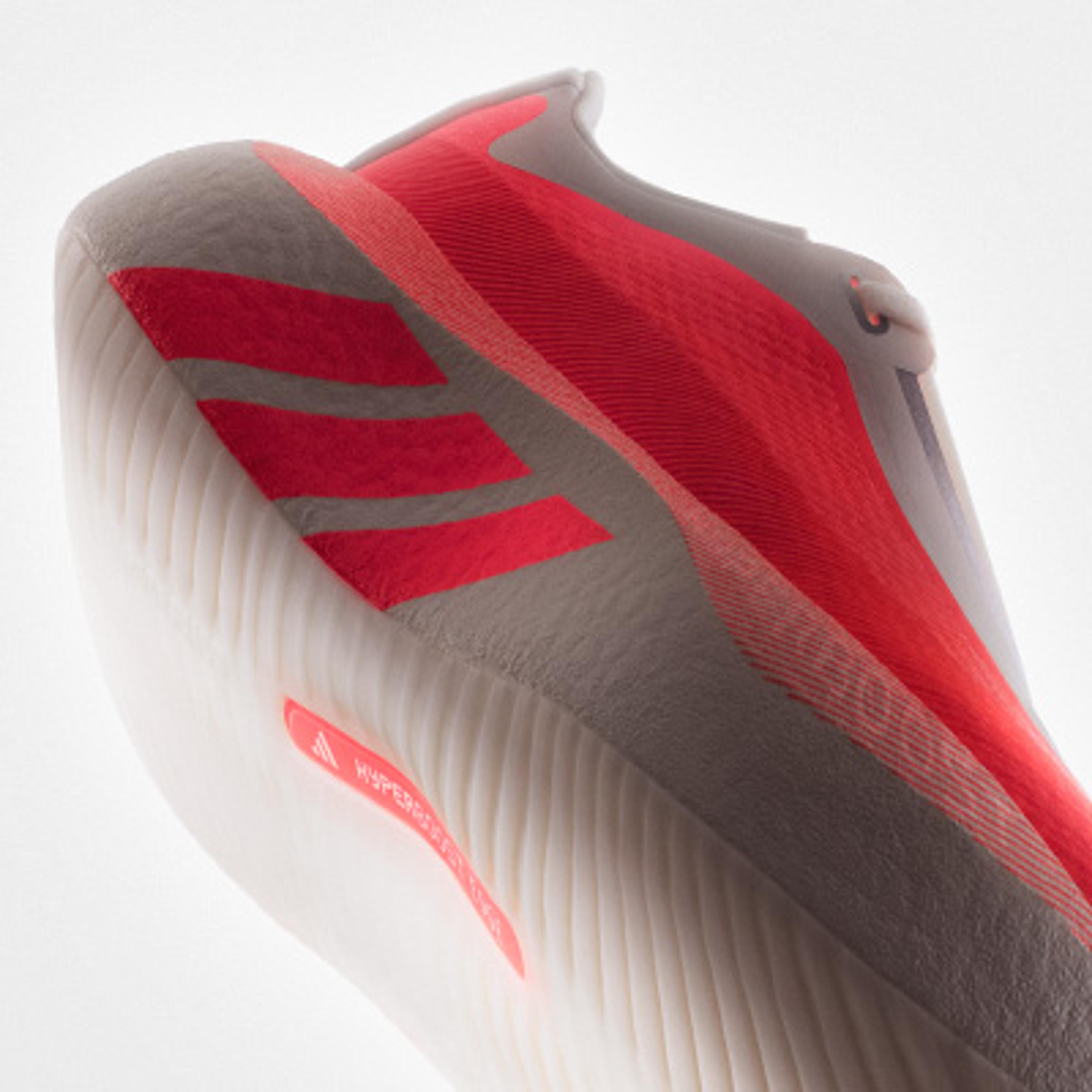 Close-up of a grey and coral Adidas athletic shoe with a textured white sole.