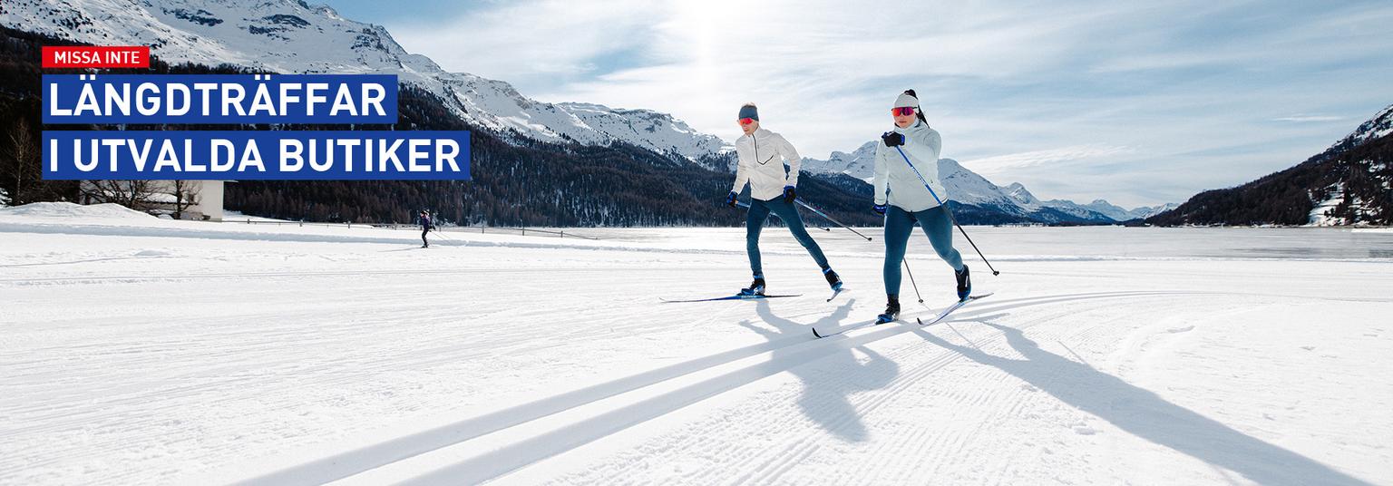 a couple of people are cross country skiing on a snowy slope .