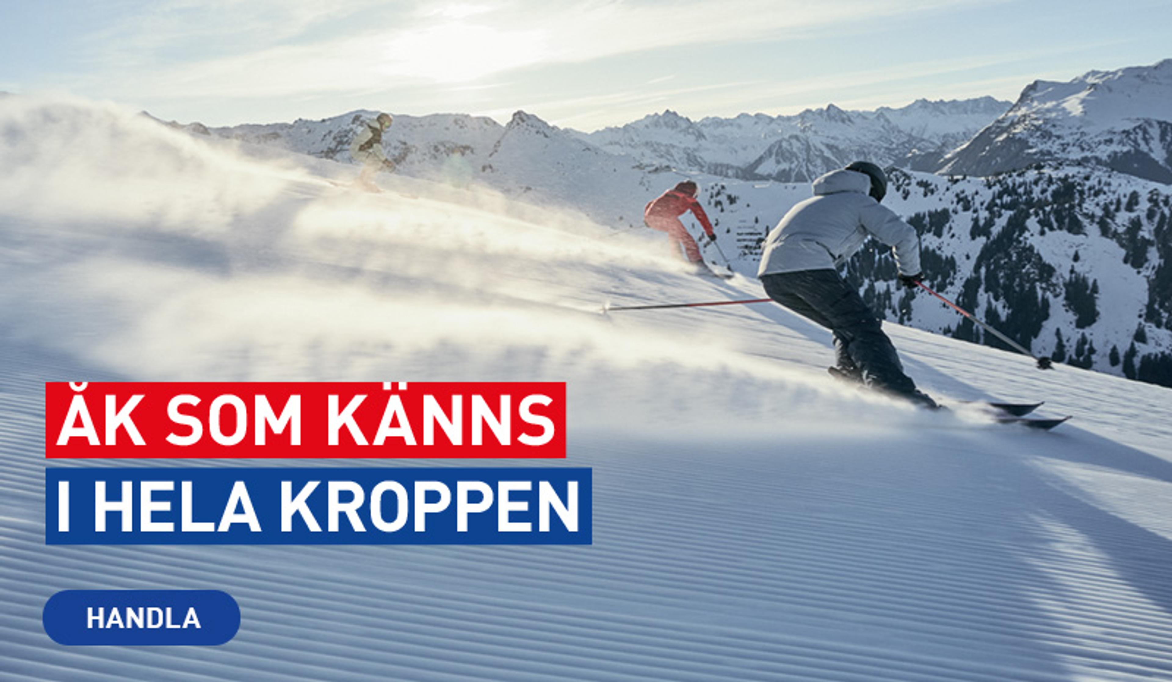 Skiers carving down a snowy mountain slope, kicking up powder.