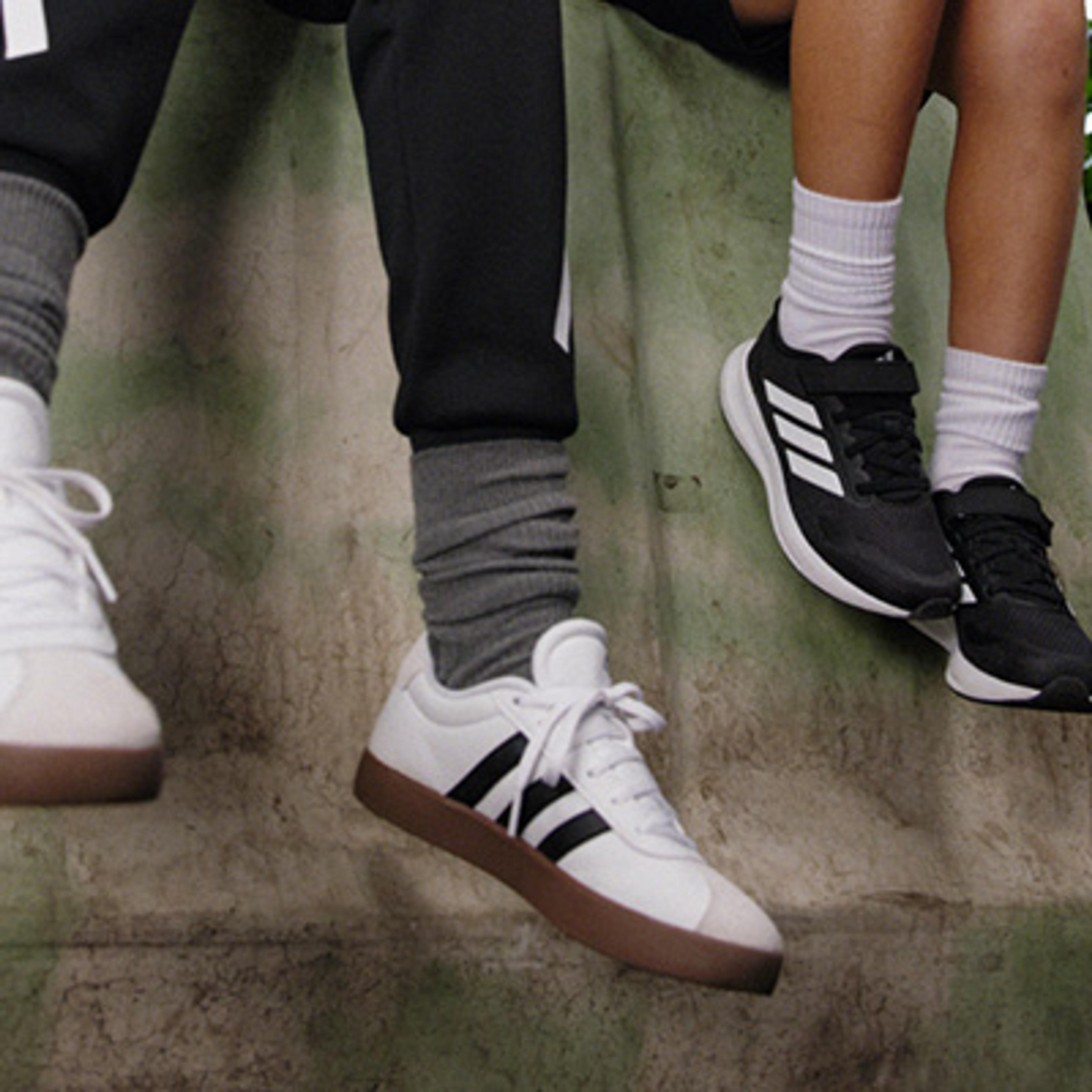 a man and a woman are sitting next to each other wearing adidas shoes .