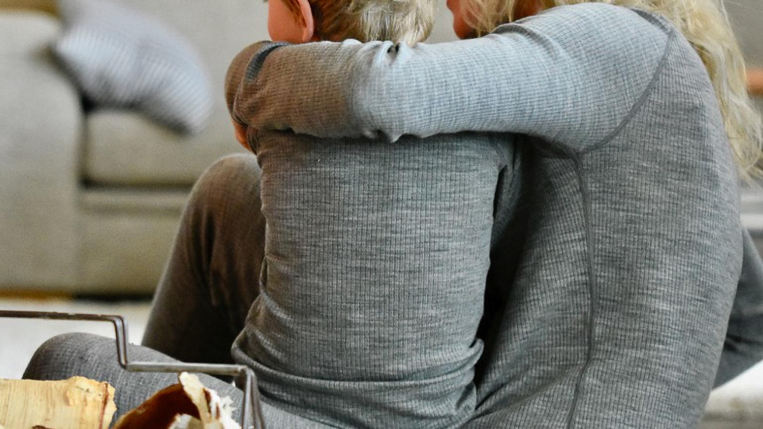 a woman and a child are sitting on the floor hugging each other .