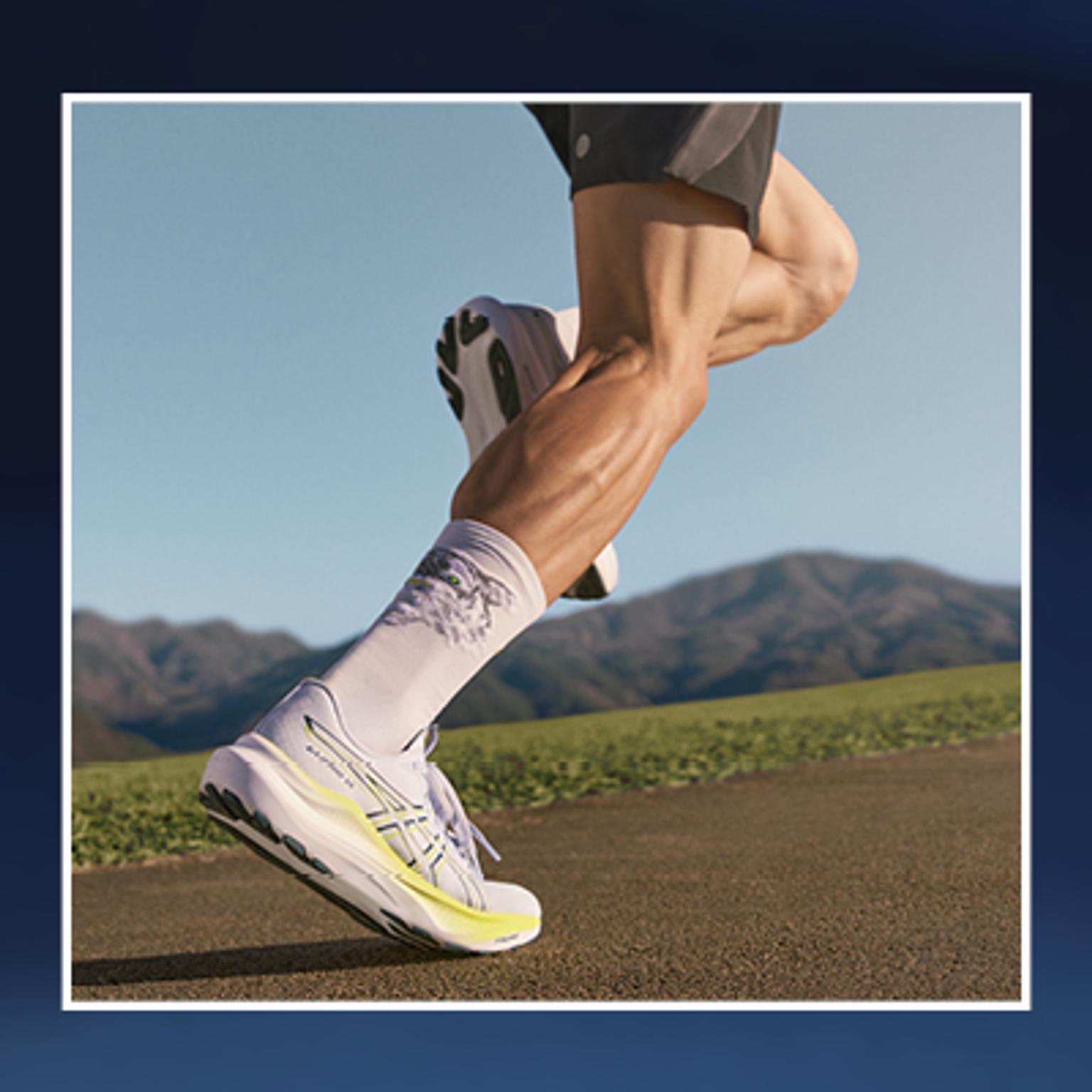 a person is running on a road wearing a pair of asics running shoes .