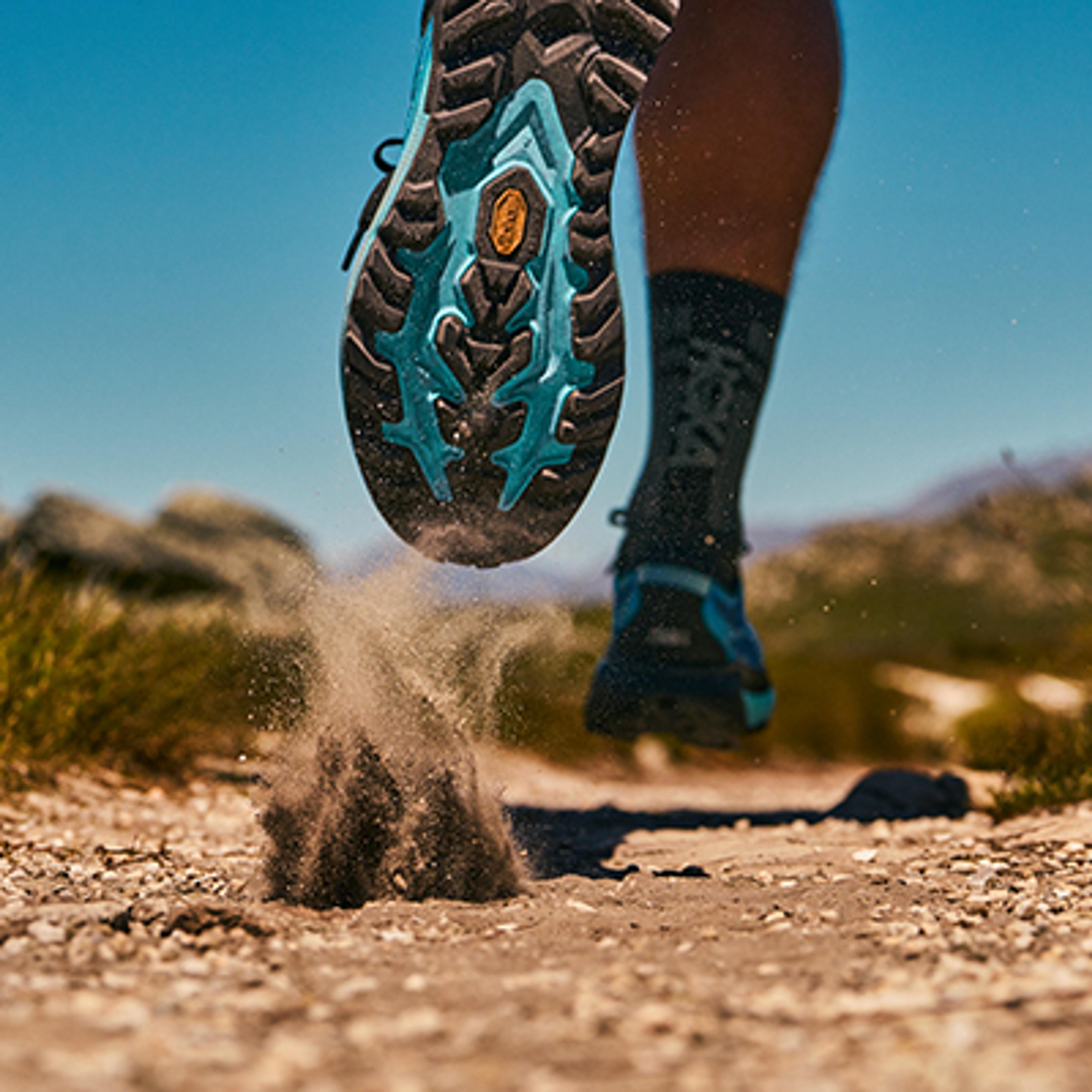 a man and a woman are running through a rocky canyon .