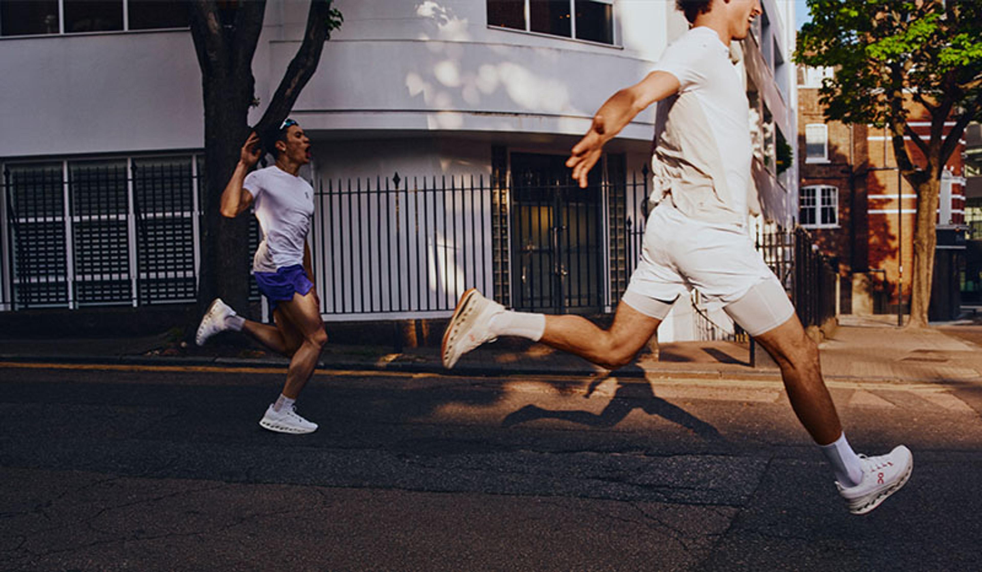 two men are running down a street in front of a building .