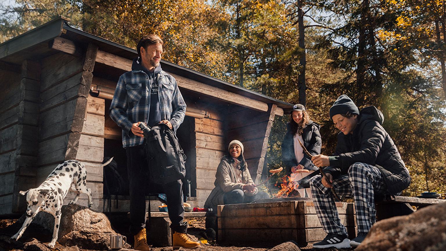 a group of people are sitting around a campfire in the woods .