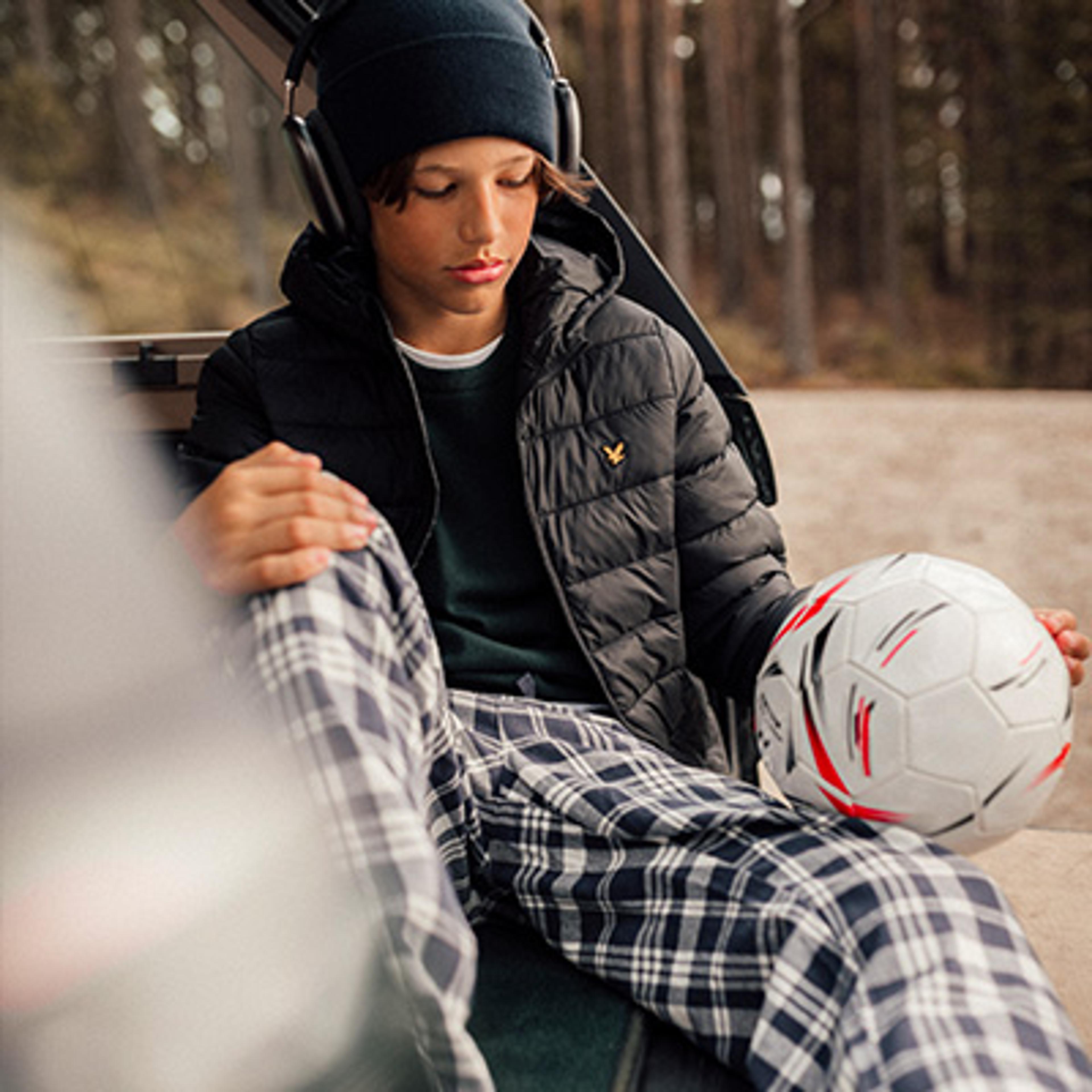 a young boy is sitting in the back of a car holding a soccer ball .