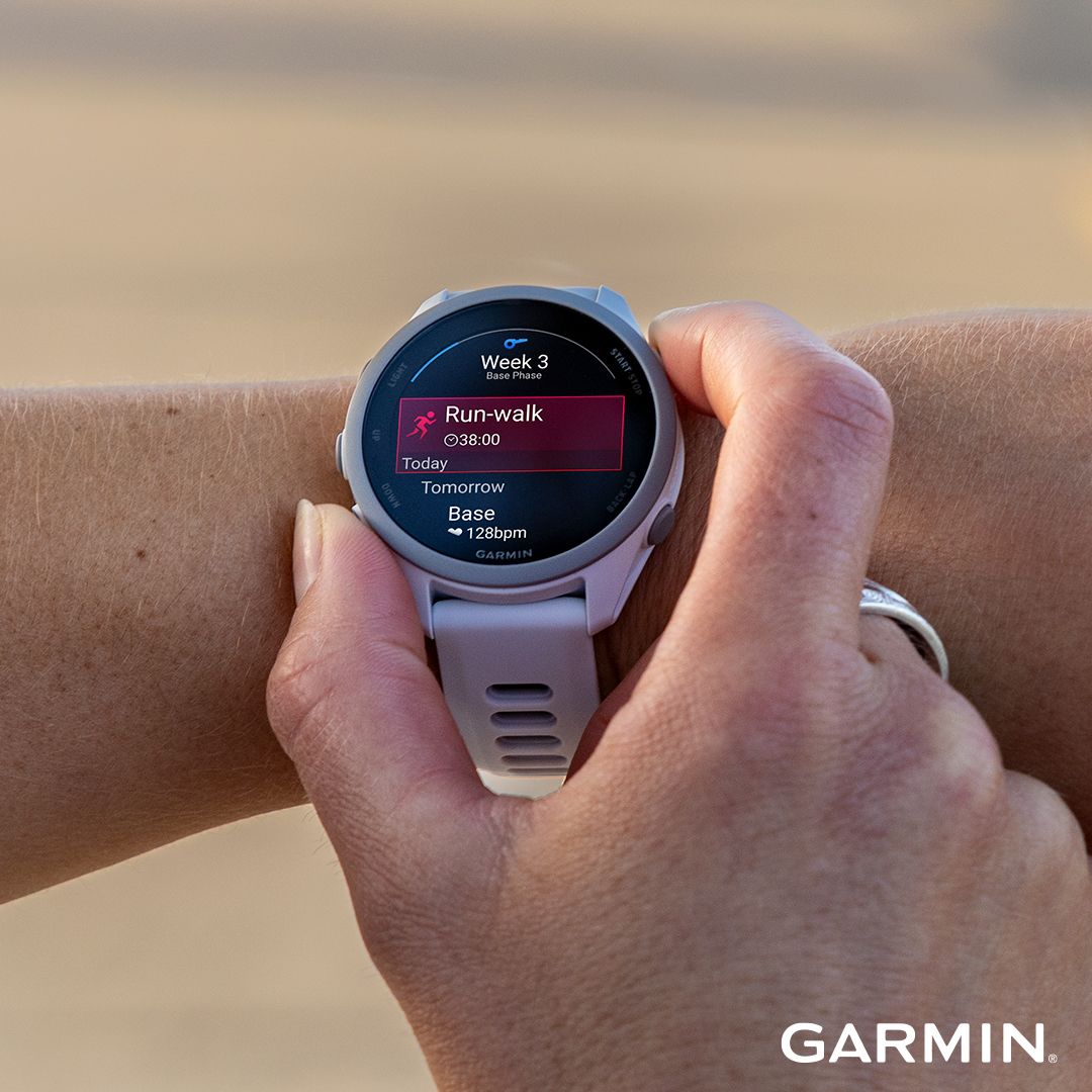 A person's hand interacts with a light-colored Garmin smartwatch displaying a "Run-walk" workout.