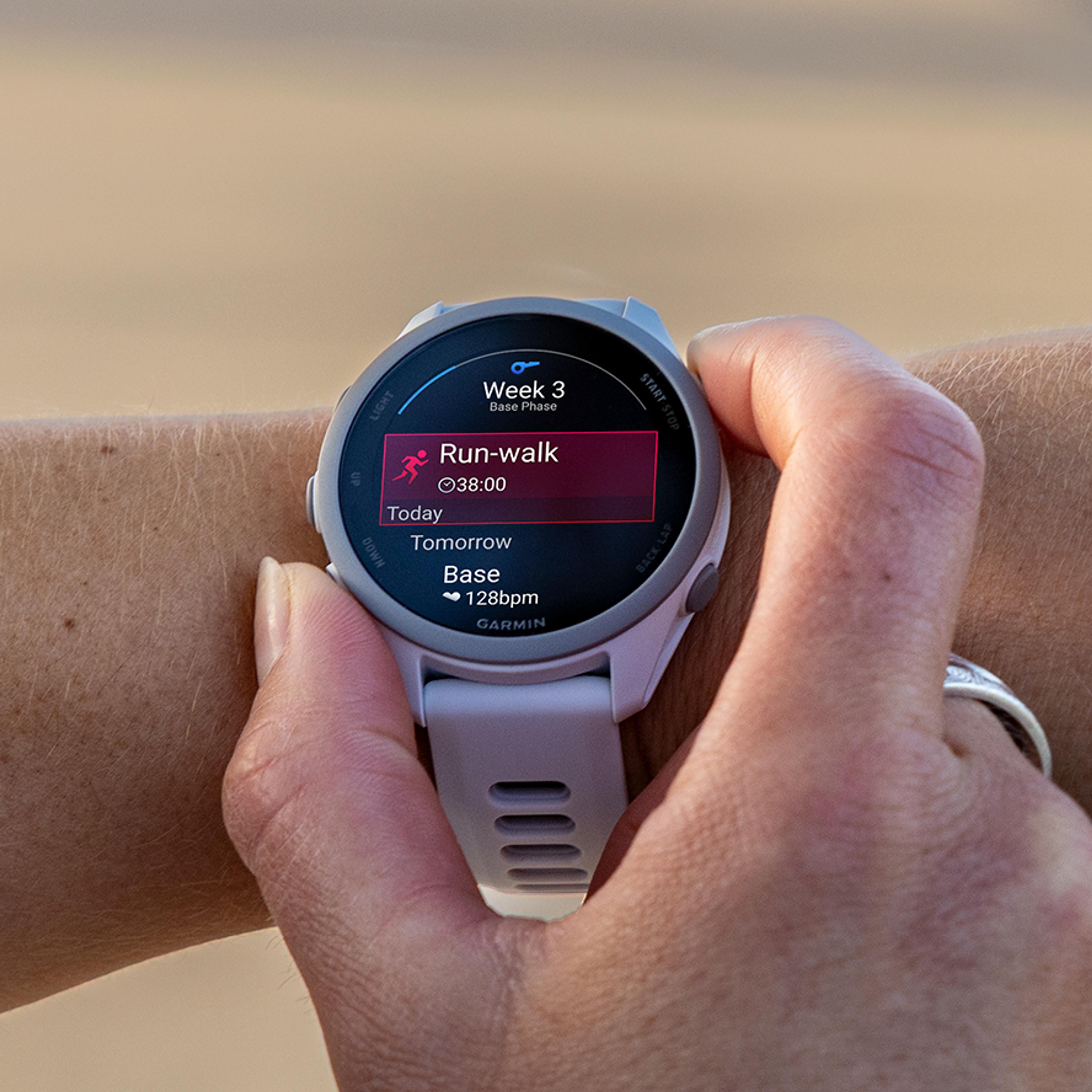 A person's hand interacts with a light-colored Garmin smartwatch displaying a "Run-walk" workout.