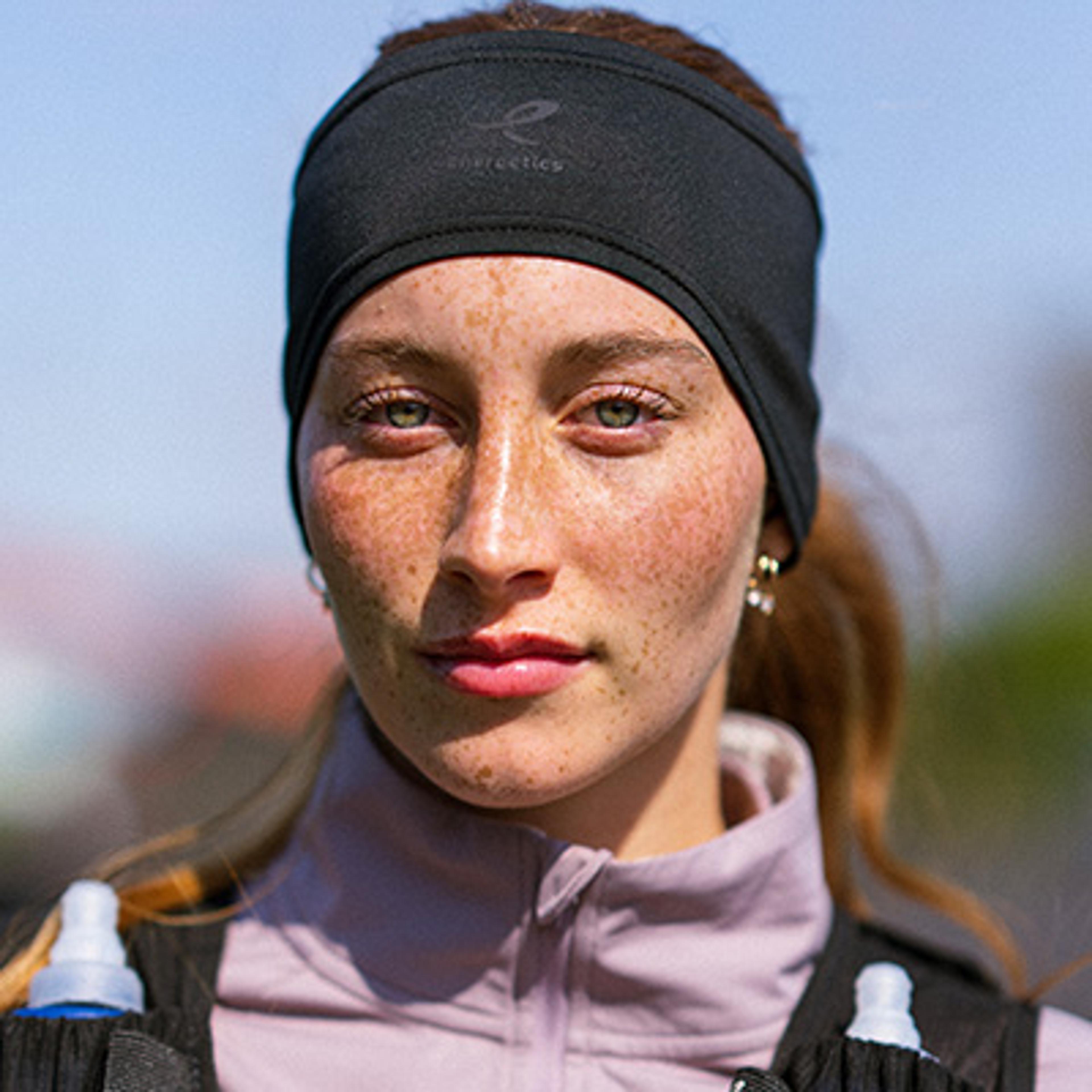 a woman wearing a headband and a backpack is looking at the camera .