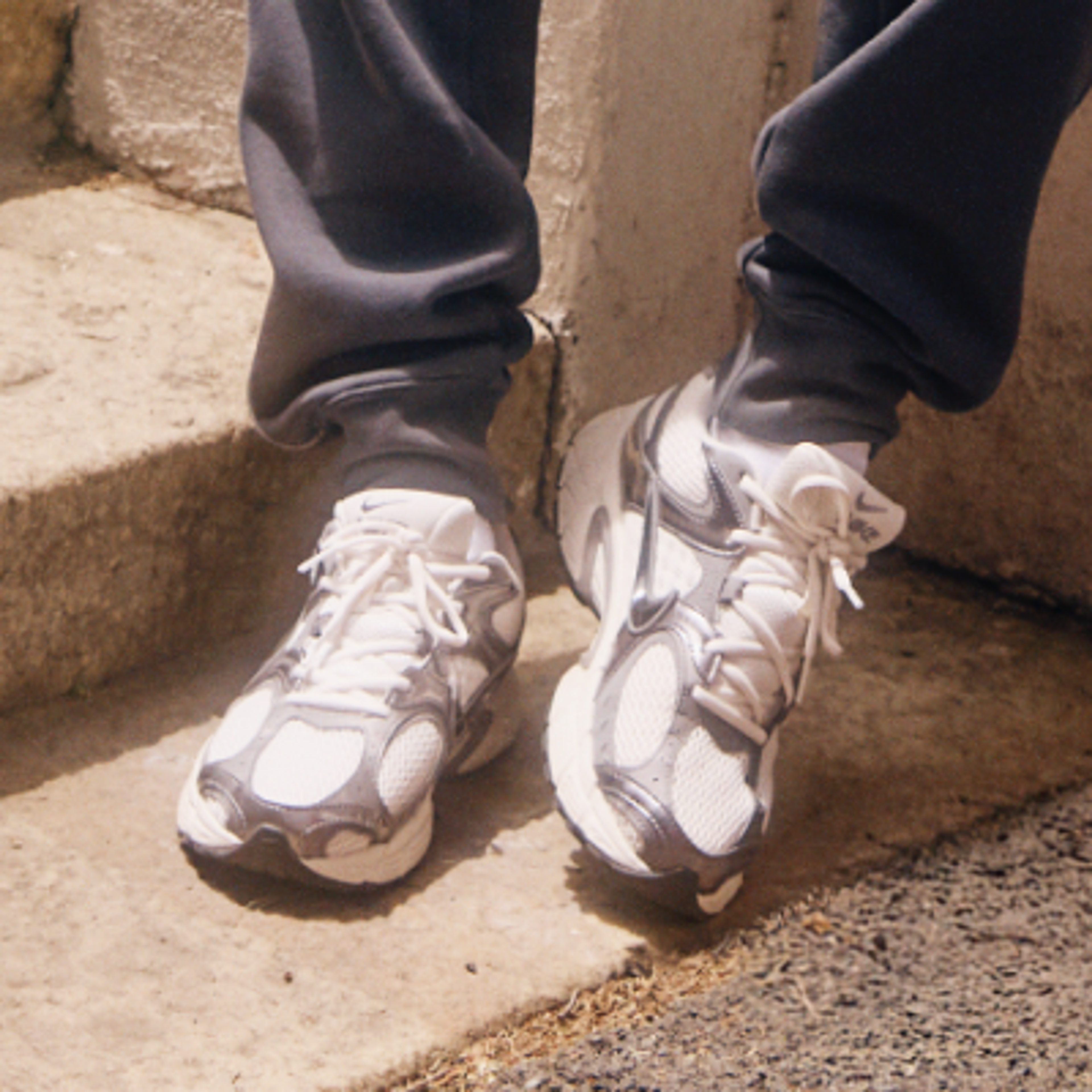 Feet in white socks and blue athletic shoes on metal stairs.