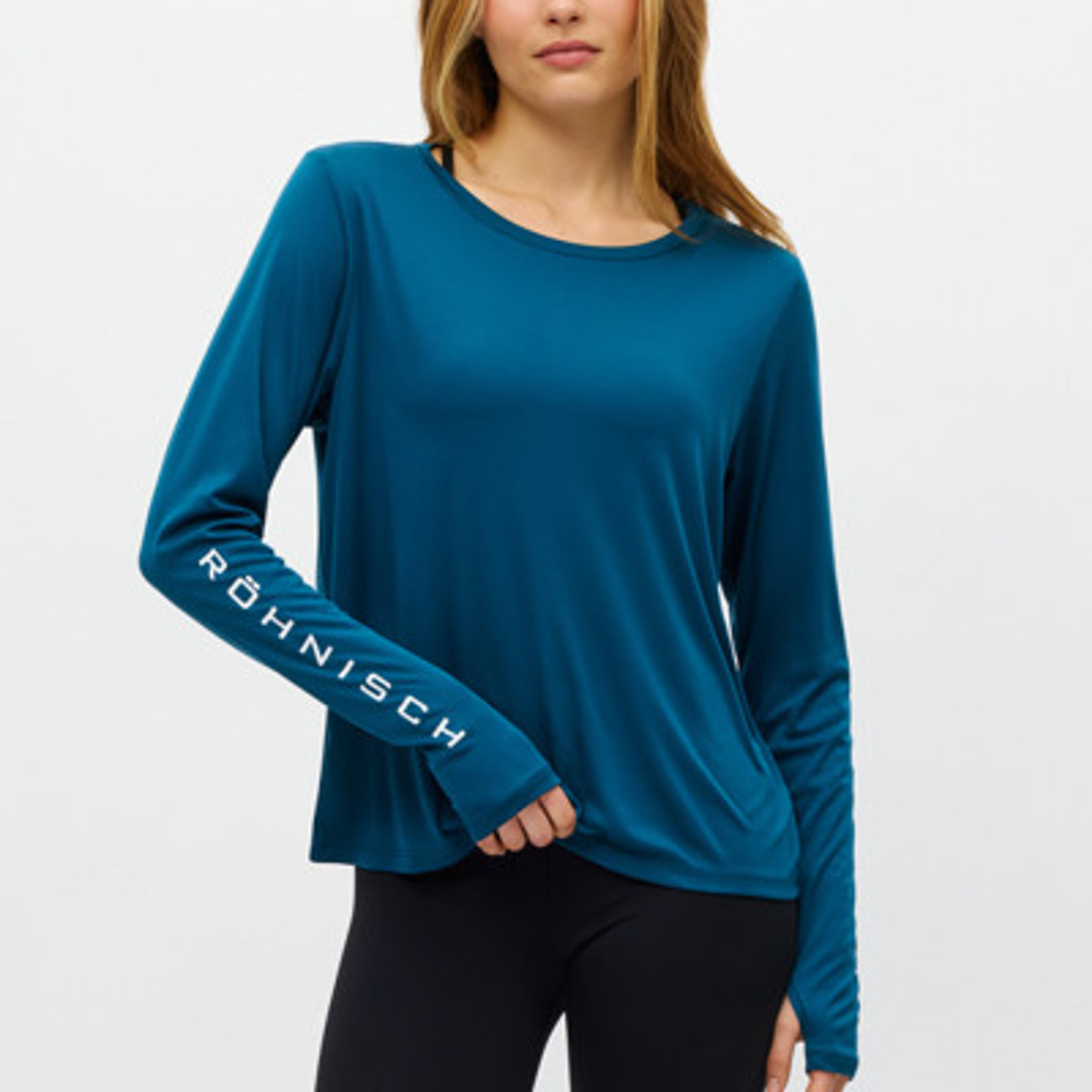 A woman wears a long-sleeved teal RÖHNISCH top.