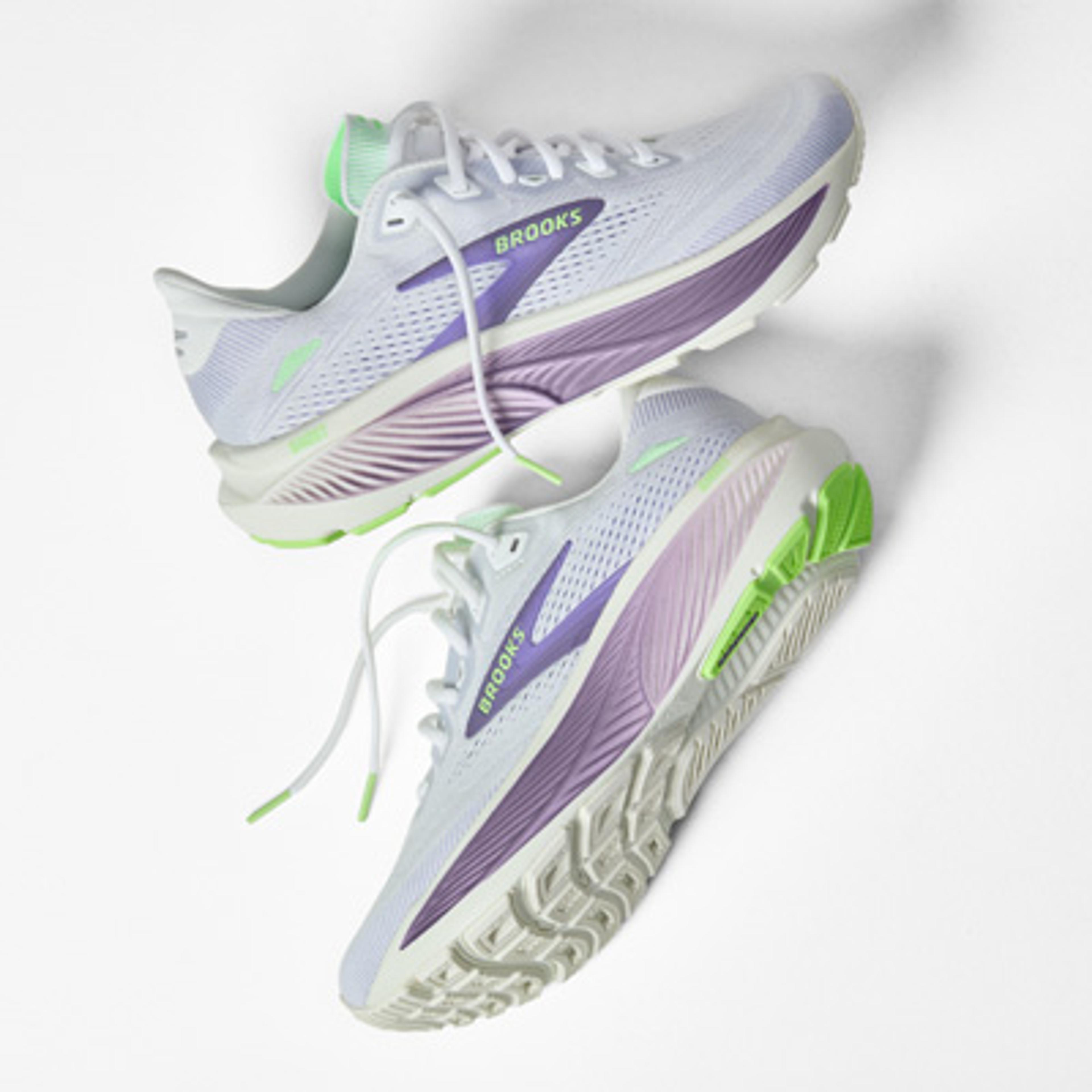 A pair of white Brooks running shoes with purple and lime green details.