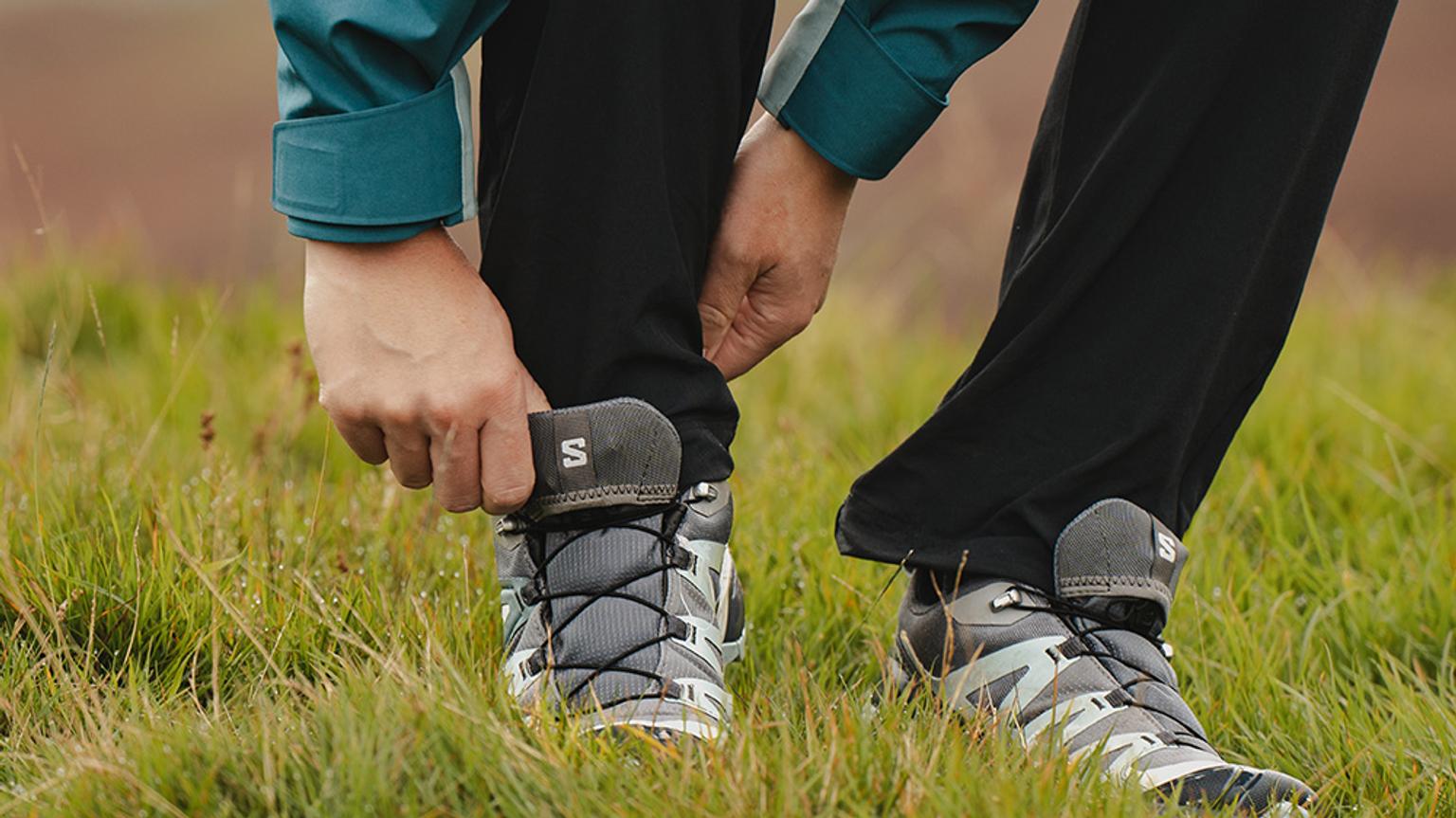 a person is tying their shoes in the grass .