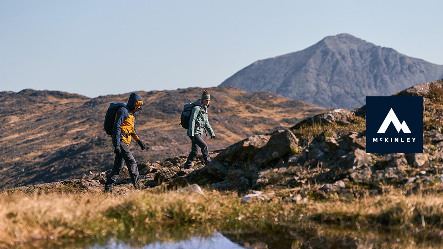 a couple of people are walking up a hill next to a mountain .