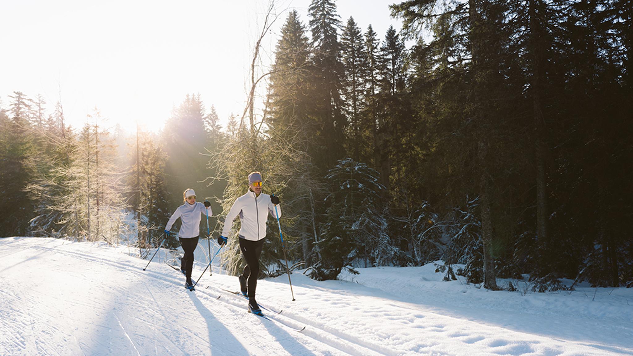 a man and a woman are cross country skiing in the snow .