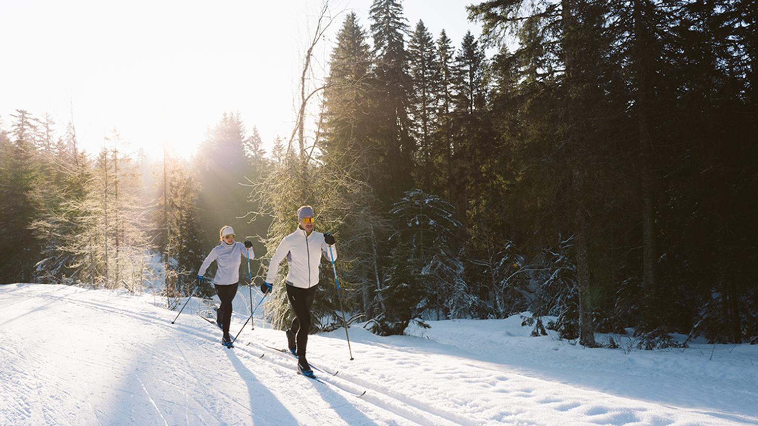 a man and a woman are cross country skiing in the snow .