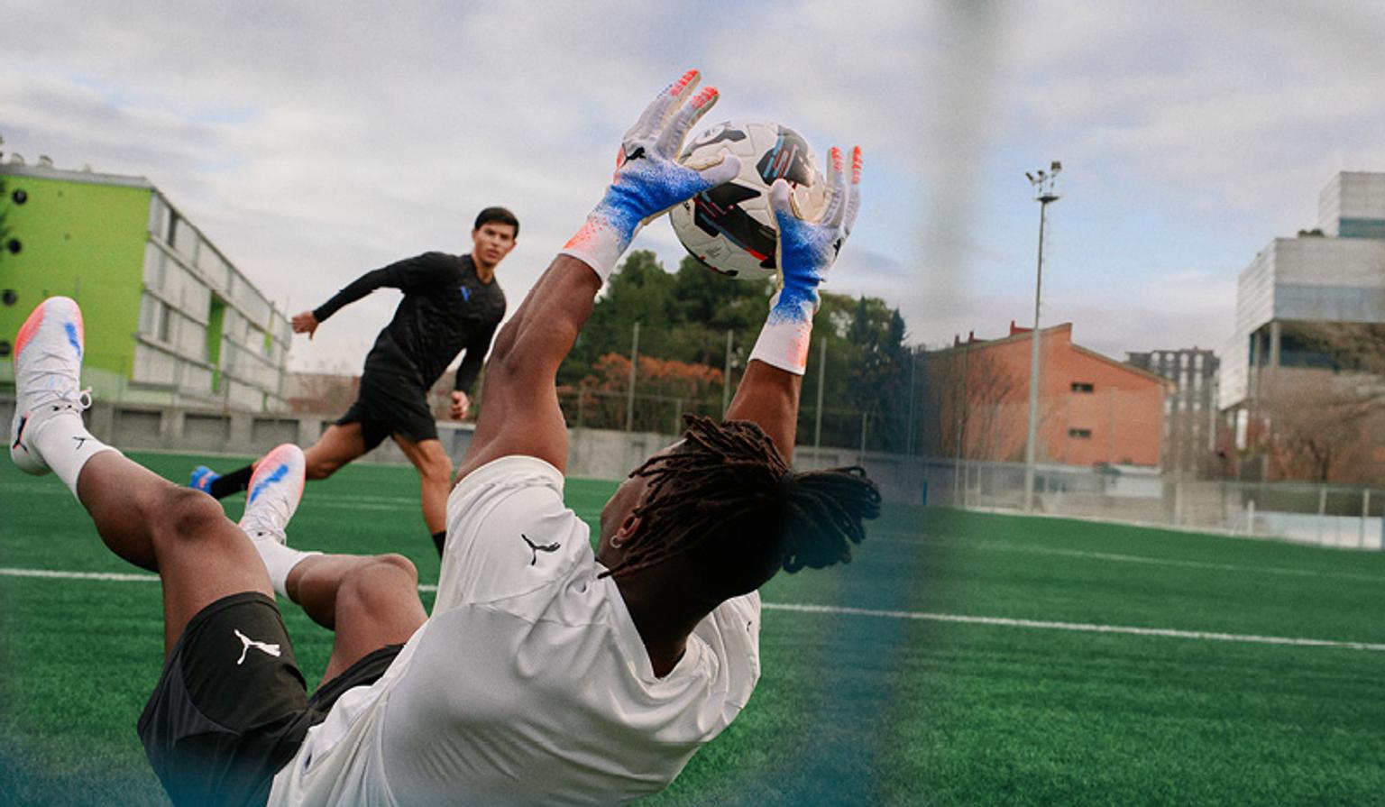 a soccer goalie is diving to catch a soccer ball on a field .