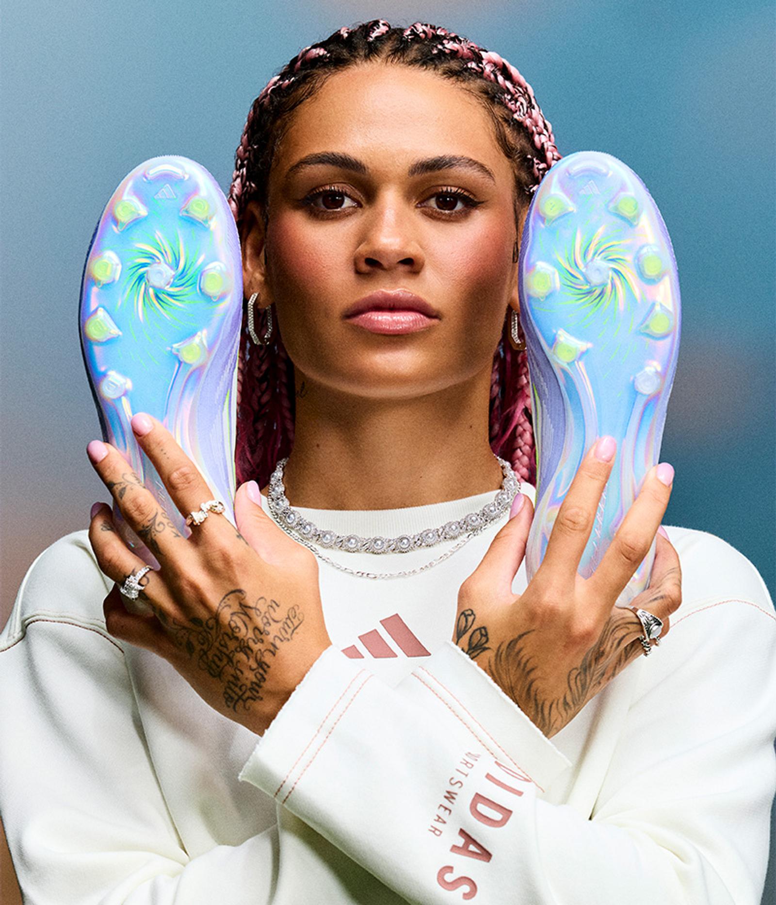 a woman is holding a pair of soccer cleats in her hands .