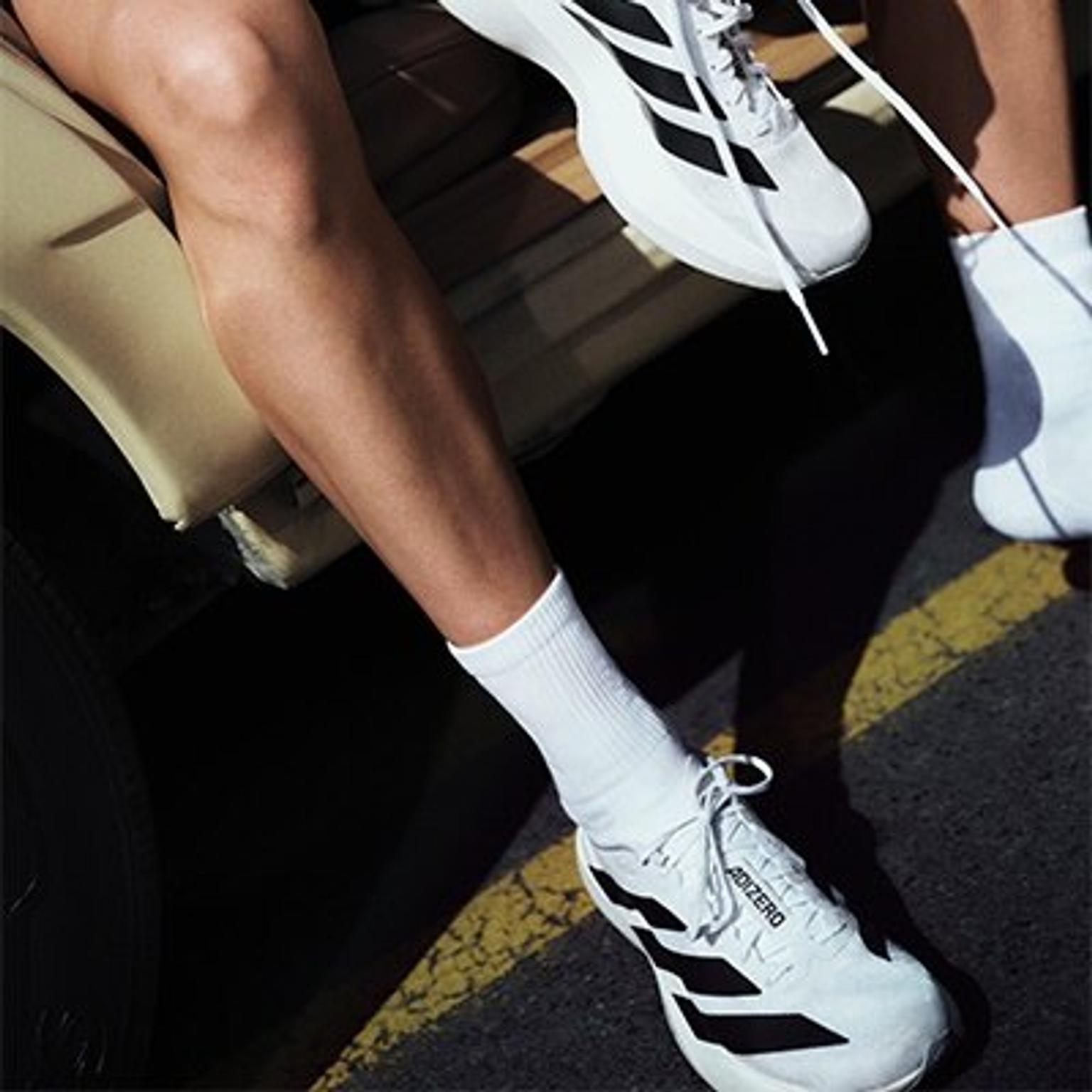 a person is wearing a pair of white and black adidas shoes .