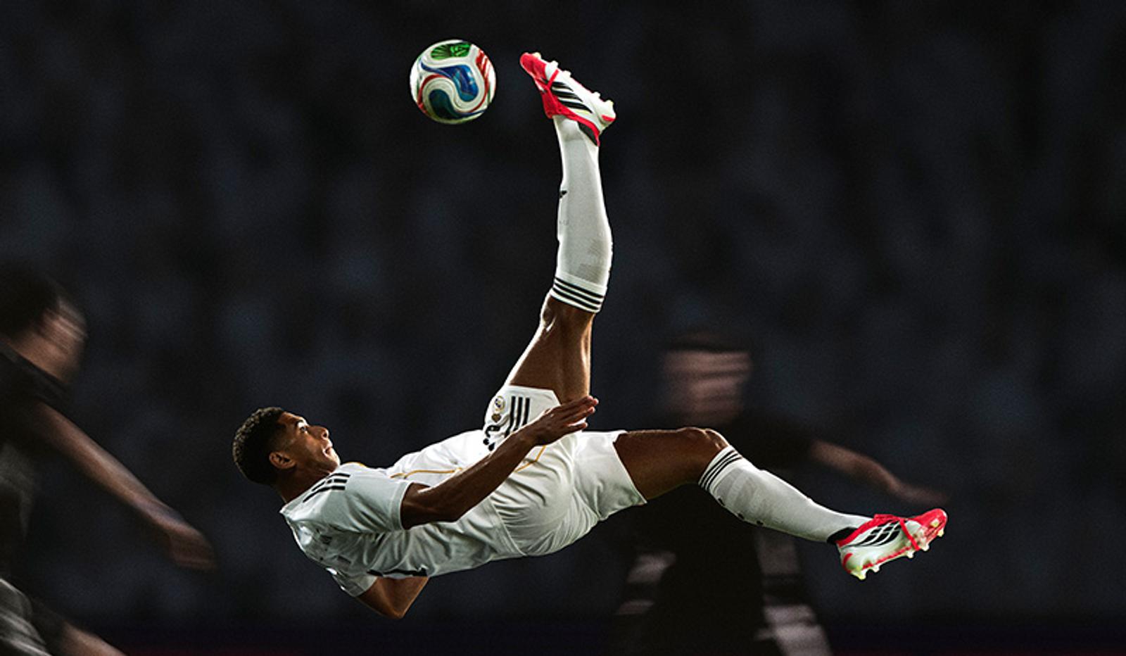 A soccer player in a white uniform performs an overhead kick.