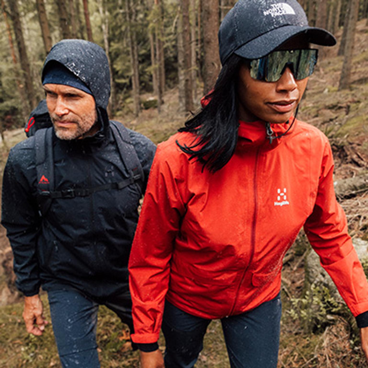 a man and a woman are walking through a forest .