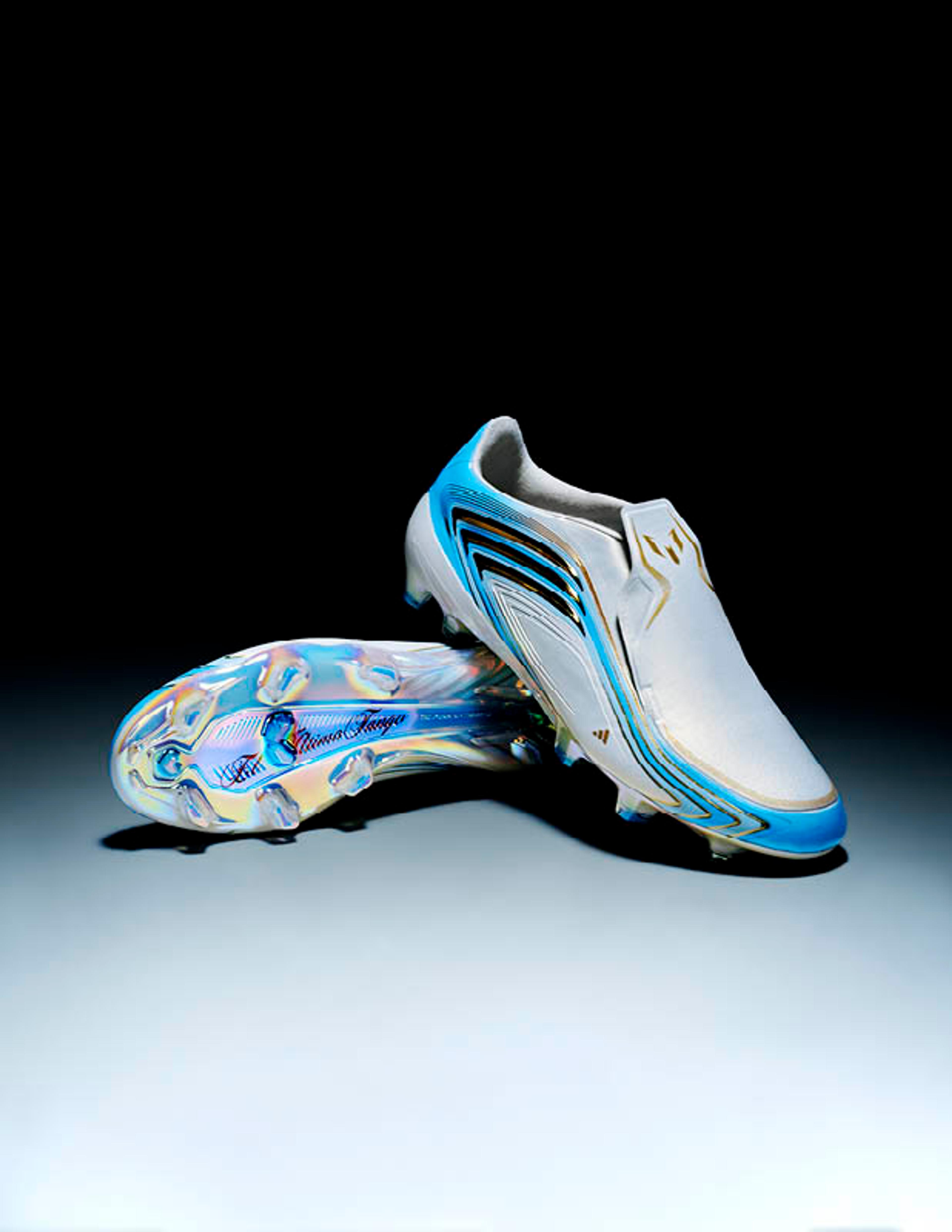 White, blue, and gold soccer cleats, one upright and one revealing its iridescent sole.