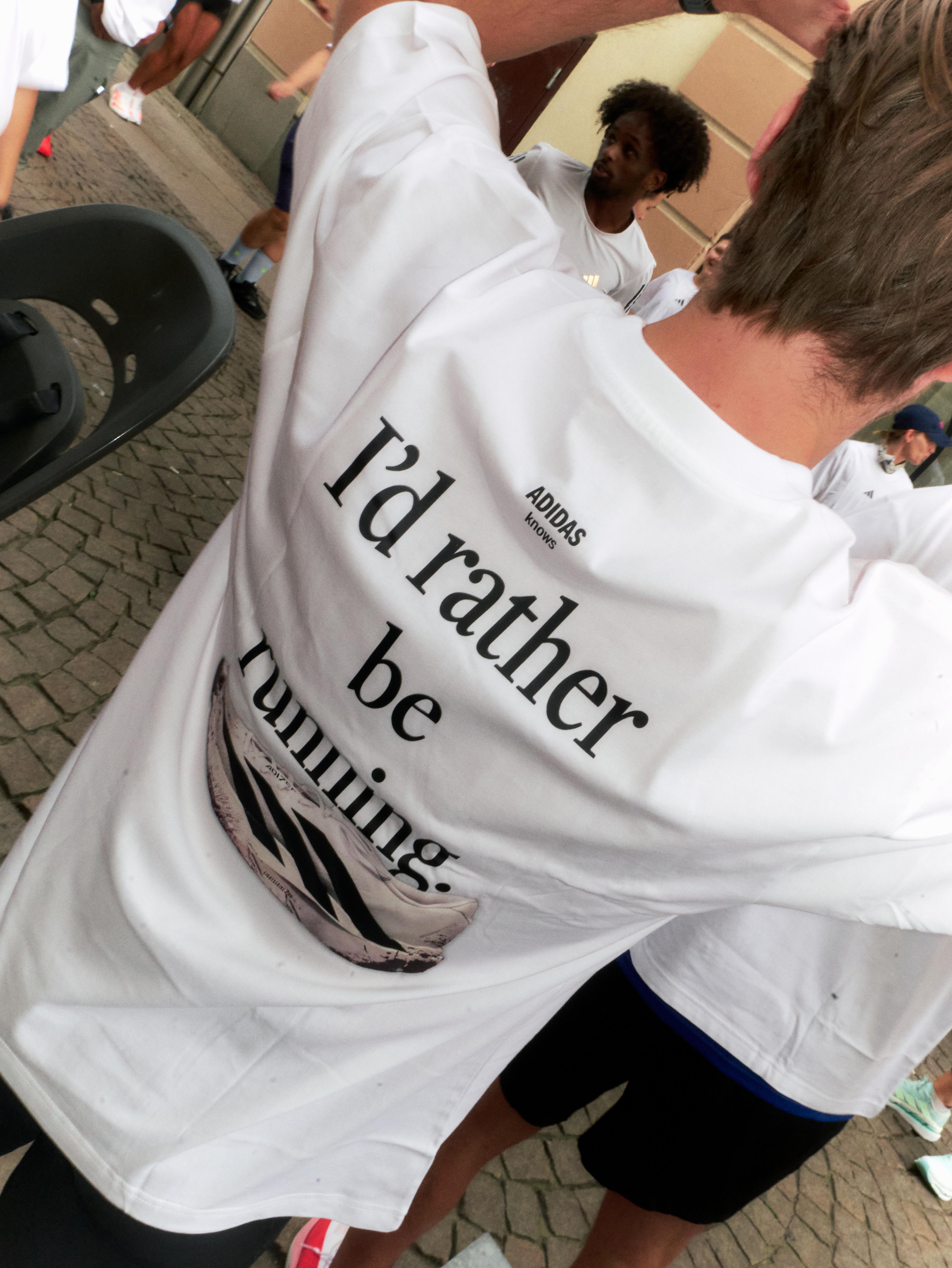 Back of a person wearing a white t-shirt with the text "I'd rather be running" and an Adidas running shoe graphic.