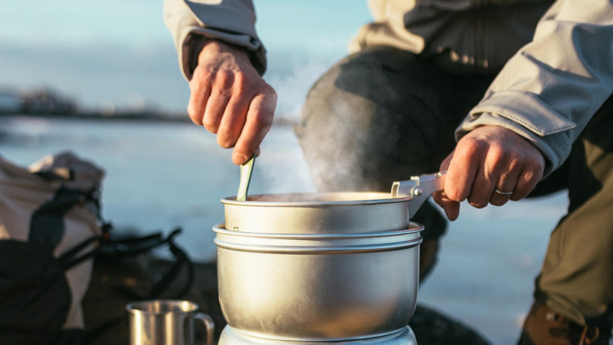 a group of people are eating outside sitting around a campfire .