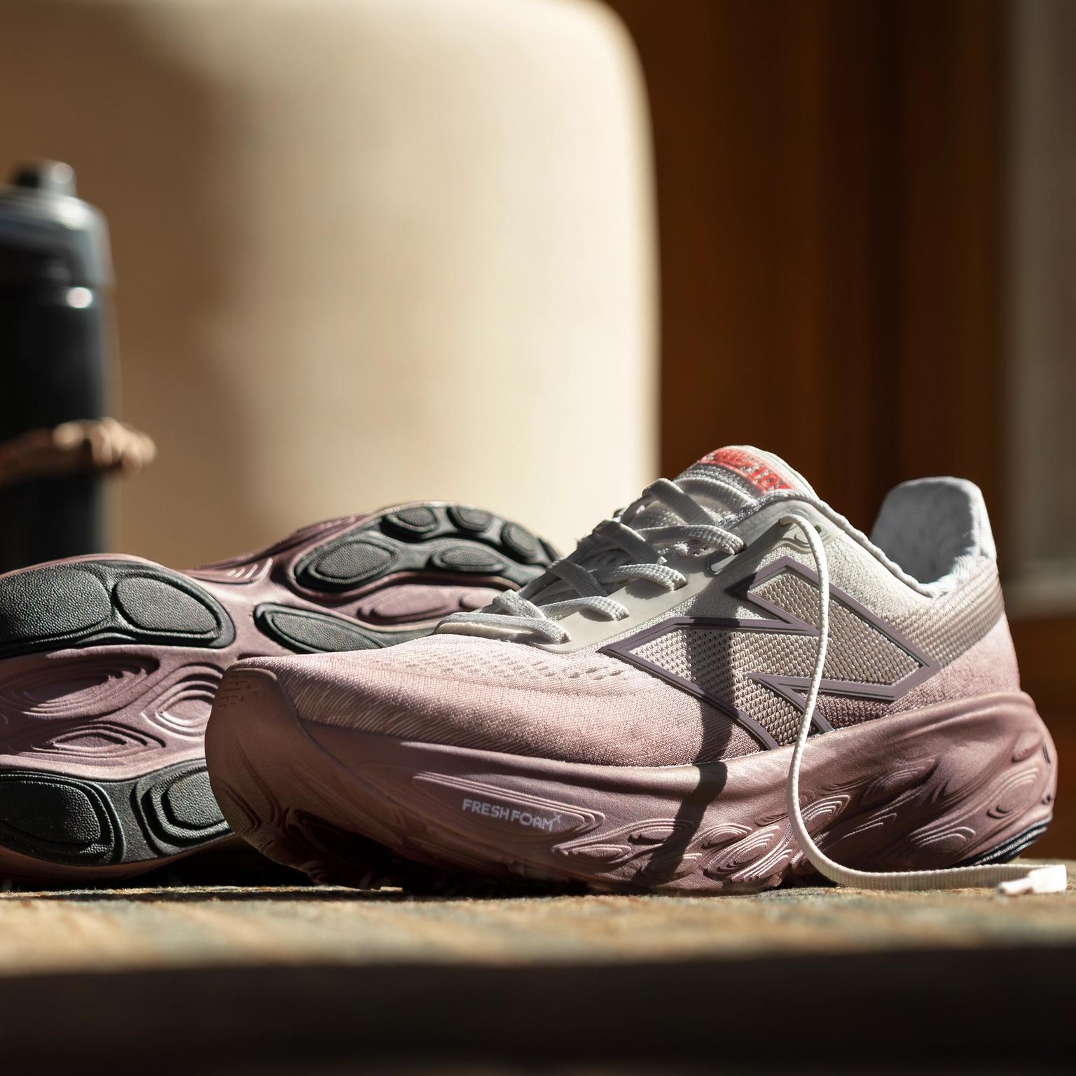 a pair of pink running shoes are sitting on a wooden table .