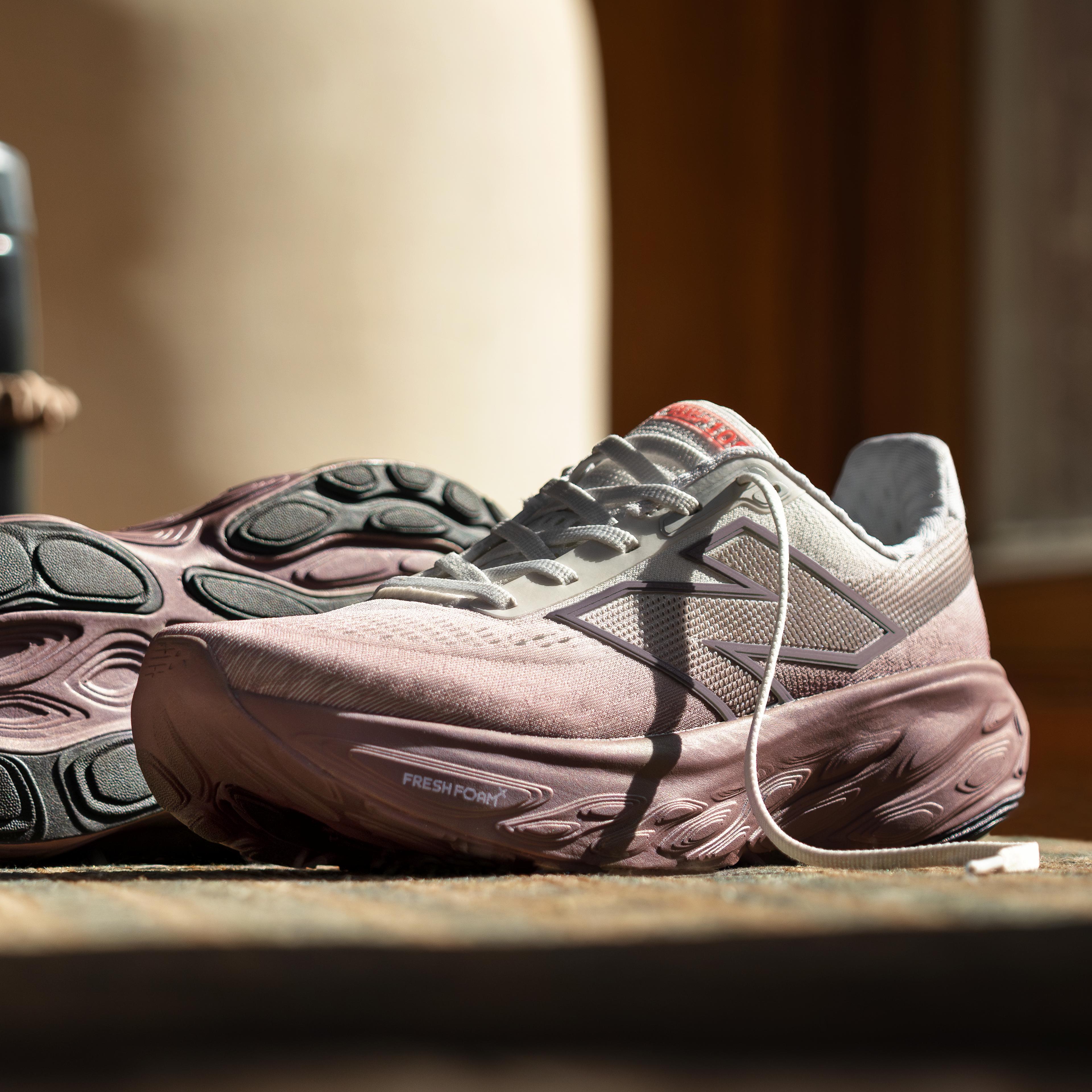 a pair of pink running shoes are sitting on a wooden table .