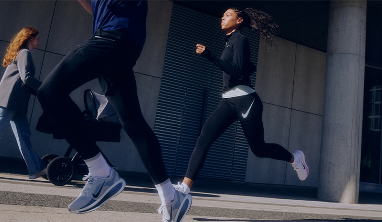 Two people running in Nike activewear on an urban street.
