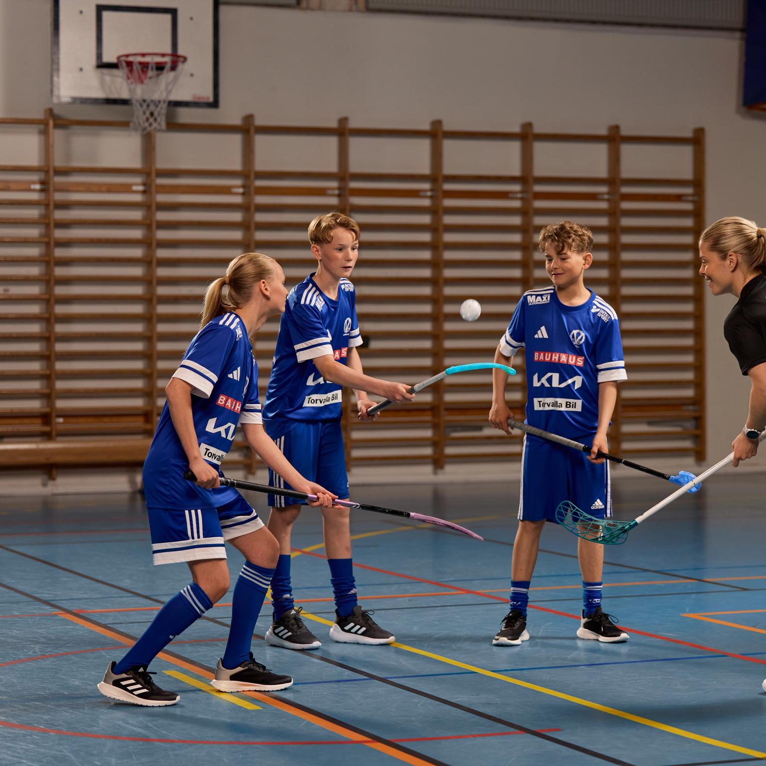 a group of young people are playing floorball in a gym .
