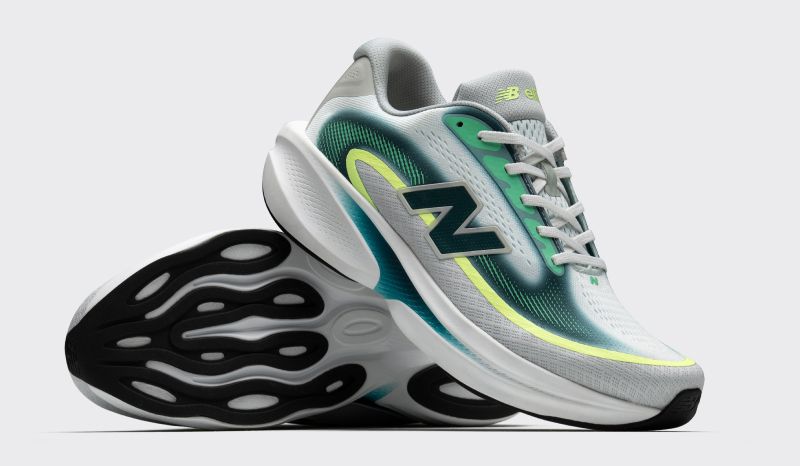 A pair of grey and white New Balance running shoes with teal and lime green accents. One shoe is tilted to show its black and white wavy sole.