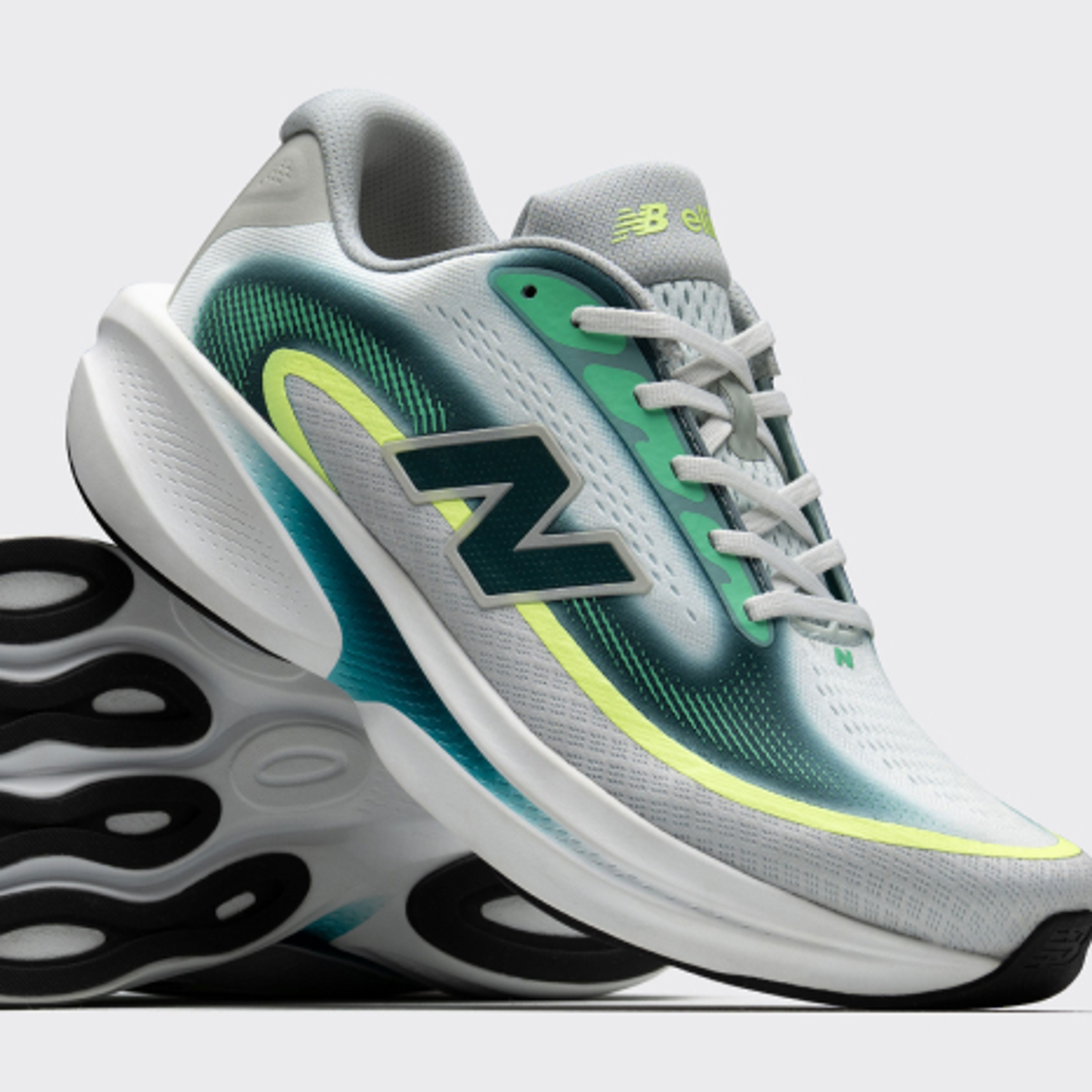 Light gray New Balance running shoes with teal and neon yellow accents, one shown upright and the other revealing its black and white patterned sole.