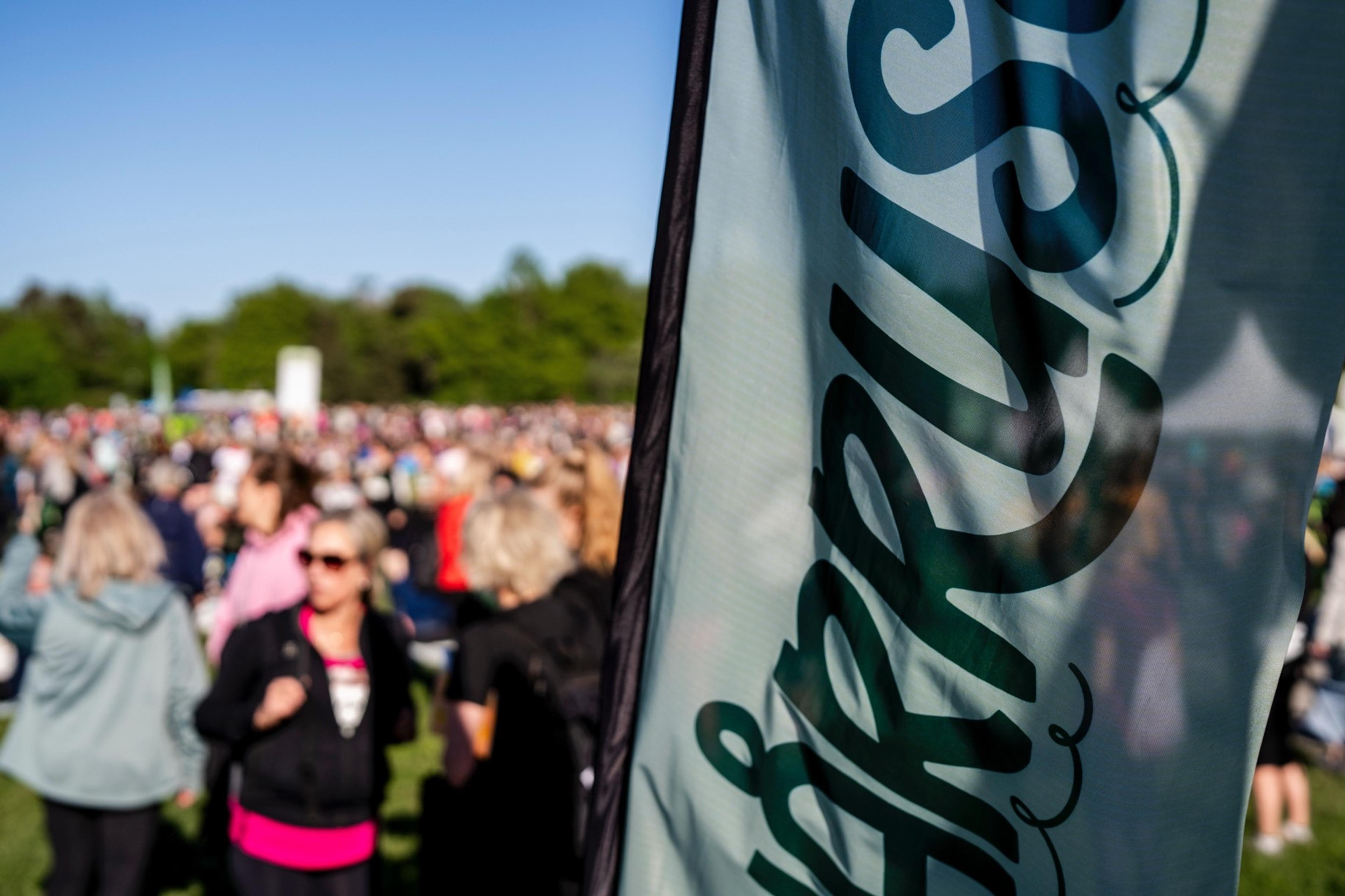 a group of people standing in a field with a flag in the foreground .