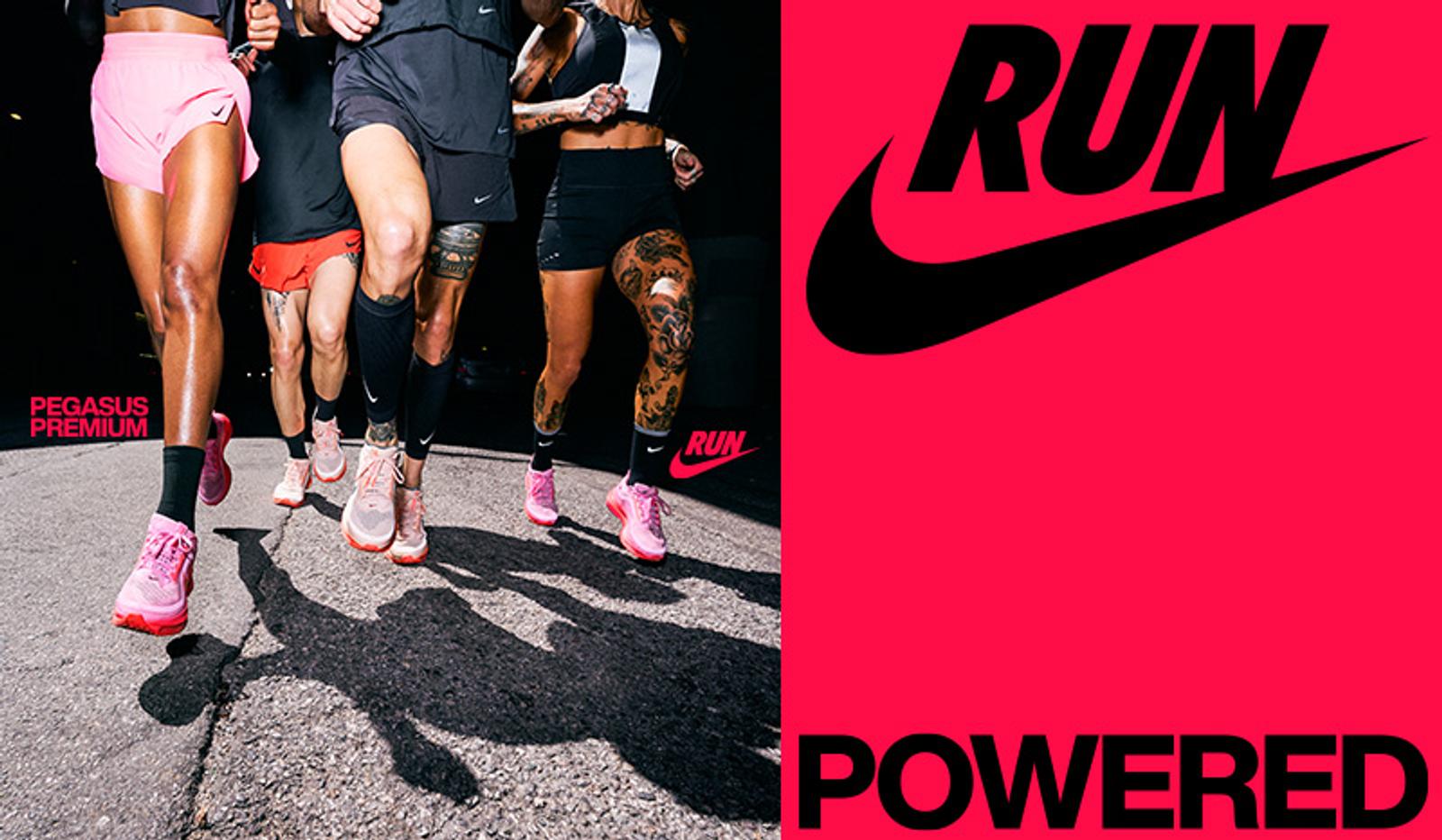 a group of people are running down a street next to a pink nike logo .