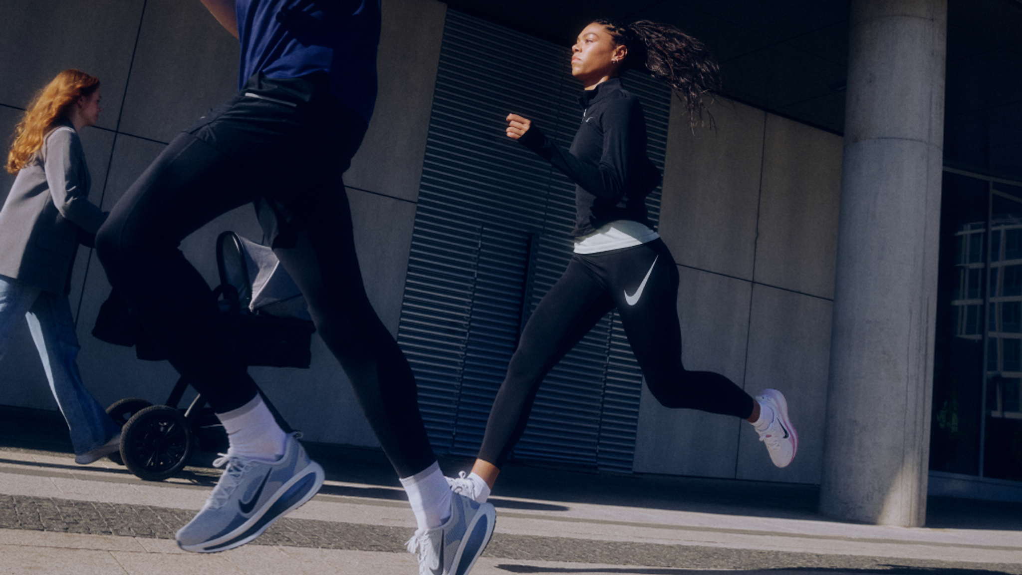 Two people running in Nike athletic wear outdoors.