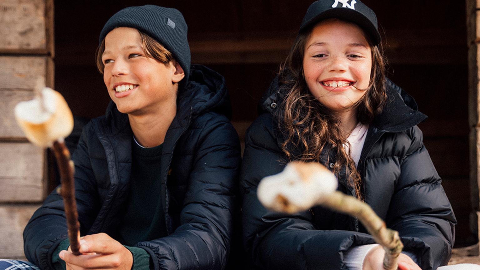 a boy and a girl are sitting next to each other eating marshmallows .