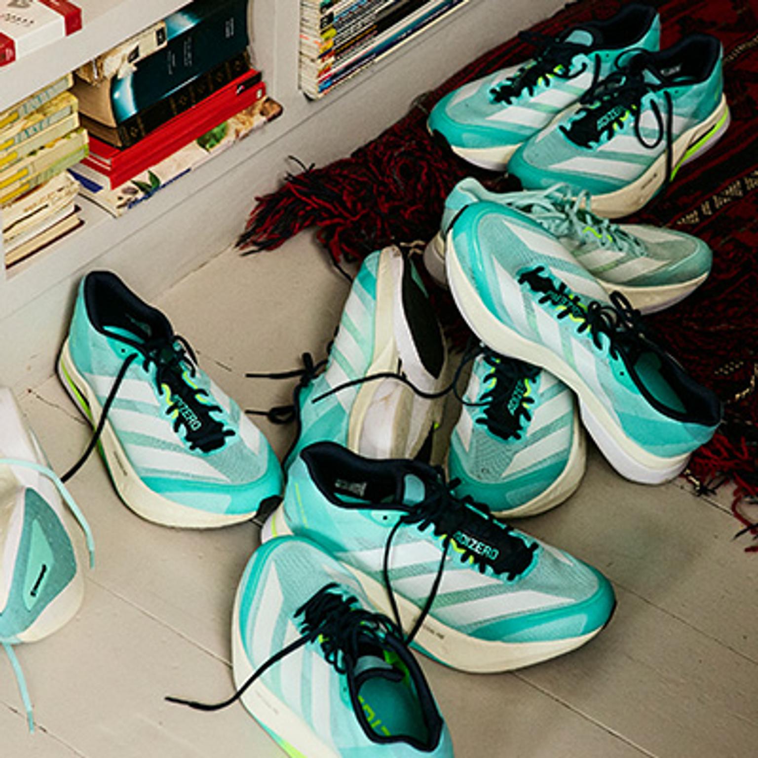 a group of running shoes are stacked on top of each other on the floor .