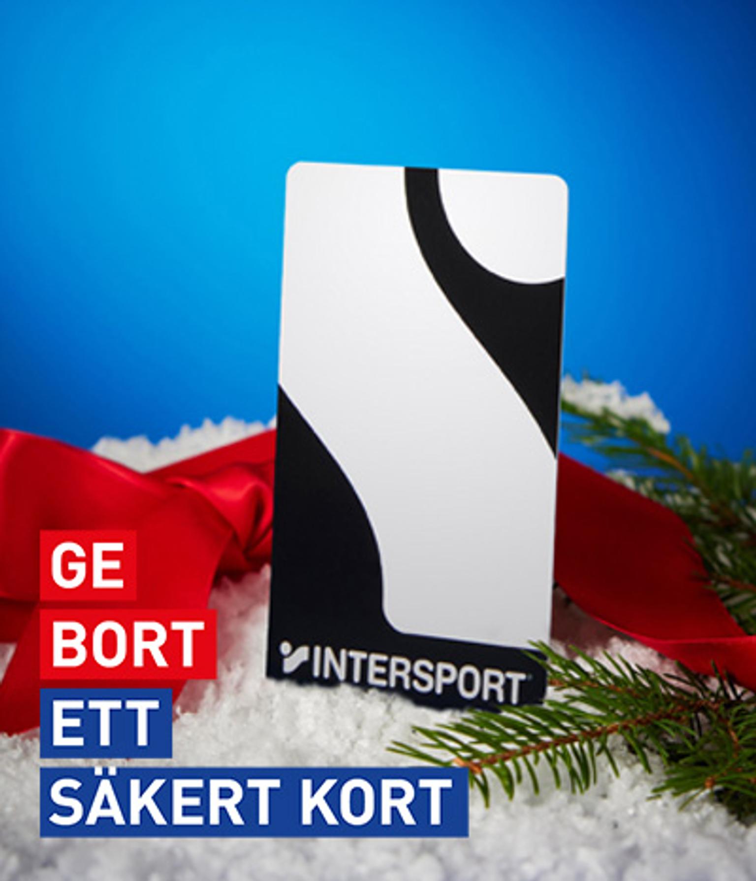 Intersport gift card in snow with red ribbon, pine branch, and blue background. Text: GE BORT ETT SÄKERT KORT.